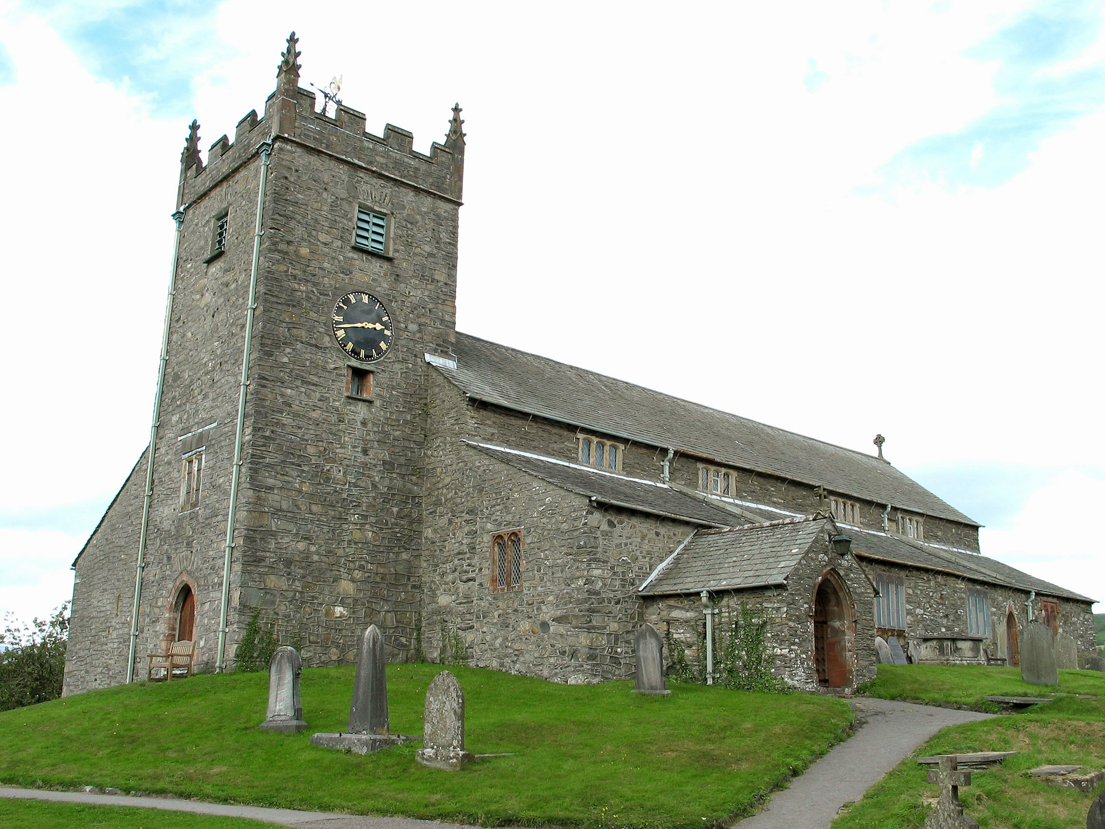 Old stone church with a tower standing on a green hill