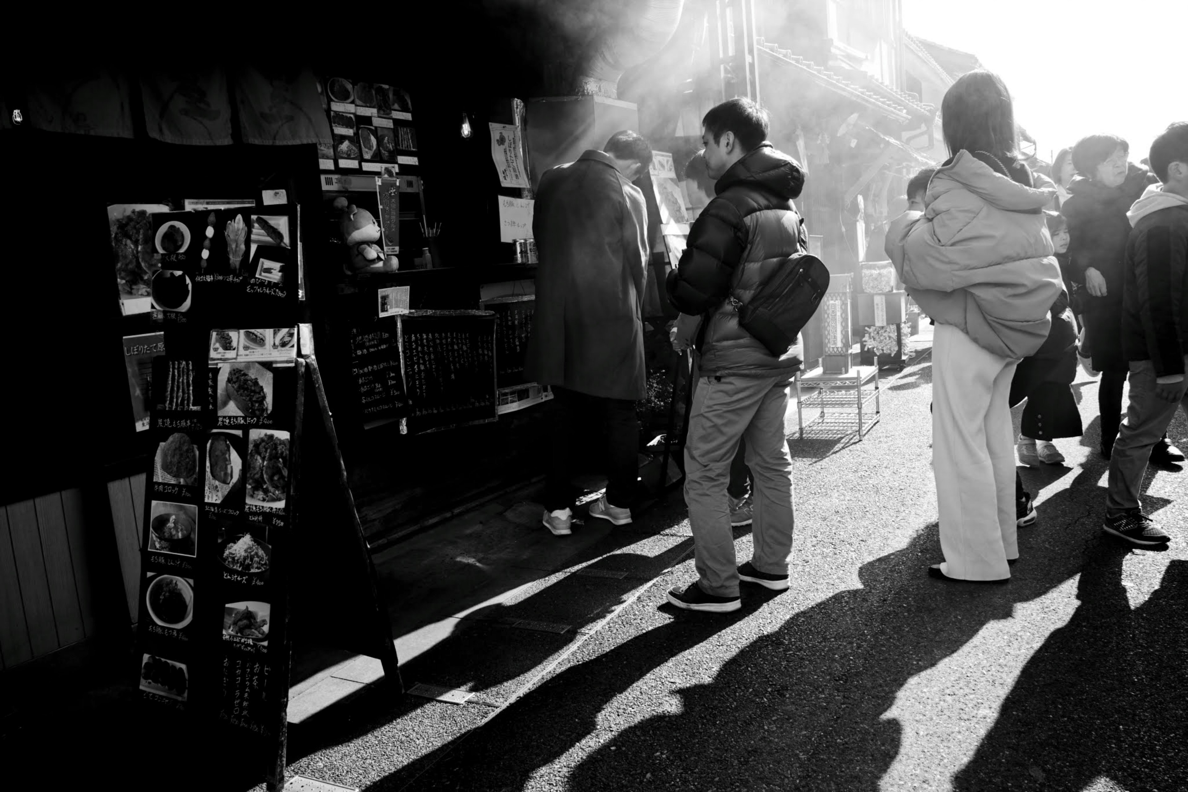 Scène de rue en noir et blanc avec des gens faisant la queue devant un magasin