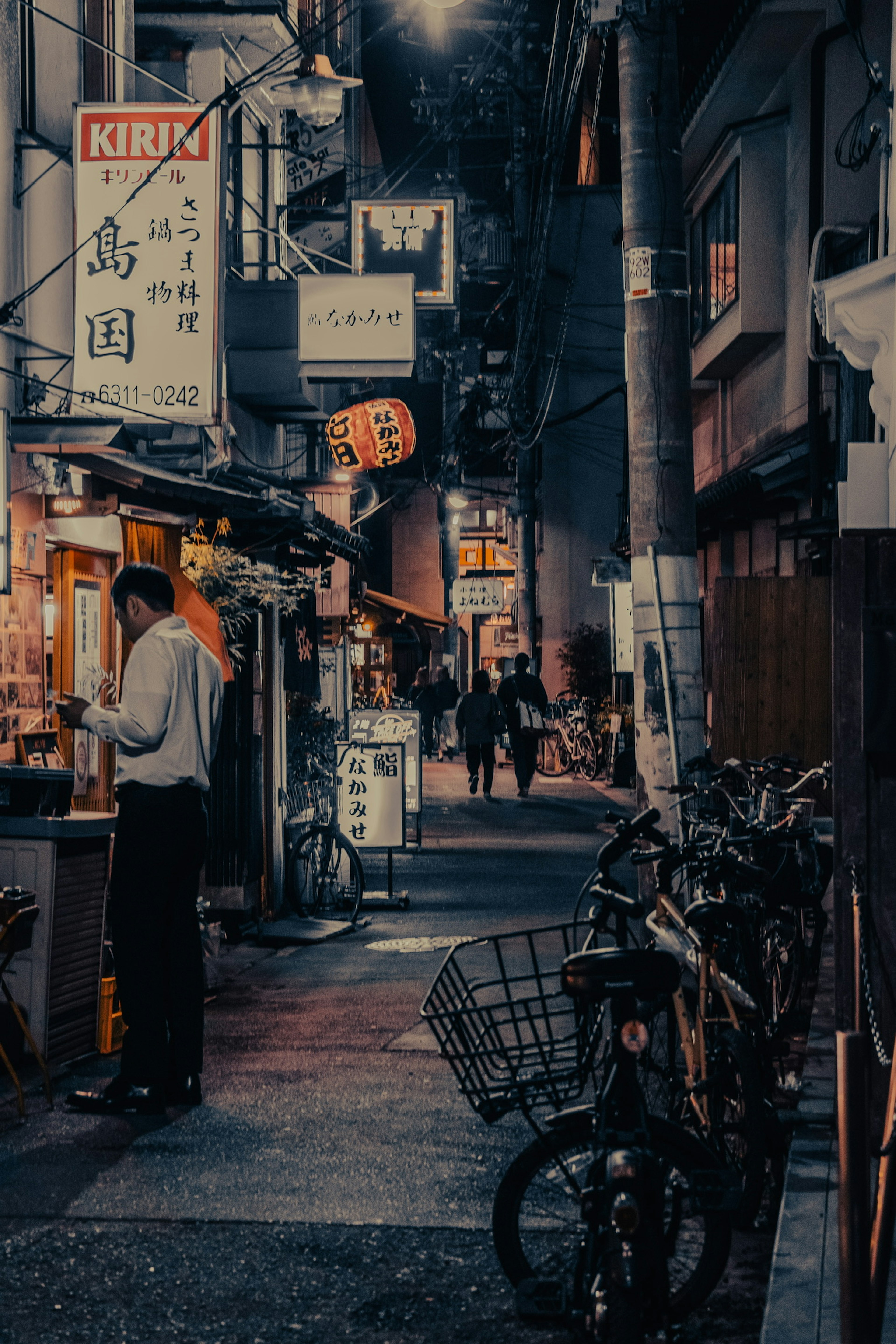 薄暗い路地に並ぶ飲食店と自転車の風景