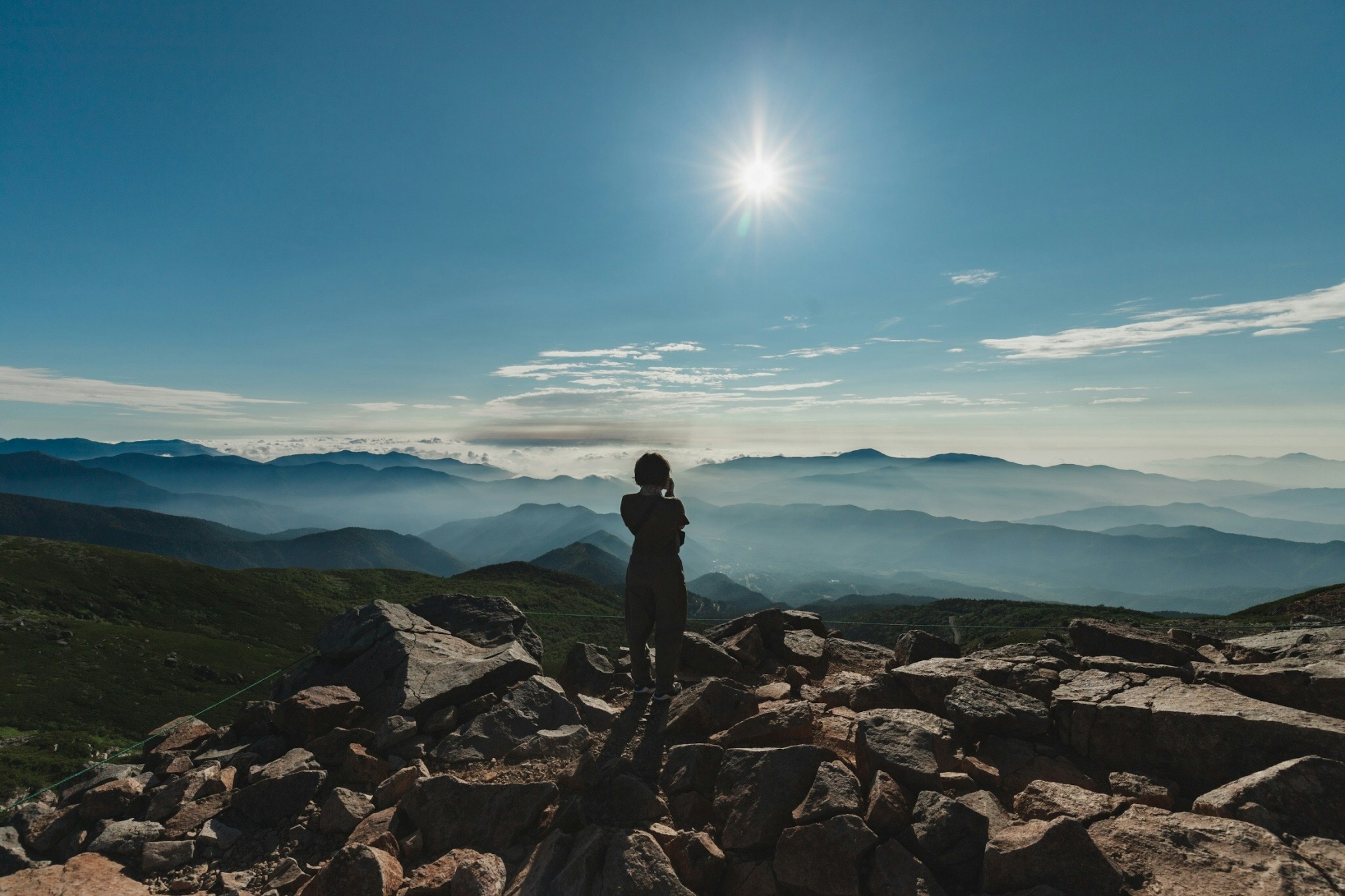 Persona in piedi su una vetta di montagna con un vasto paesaggio