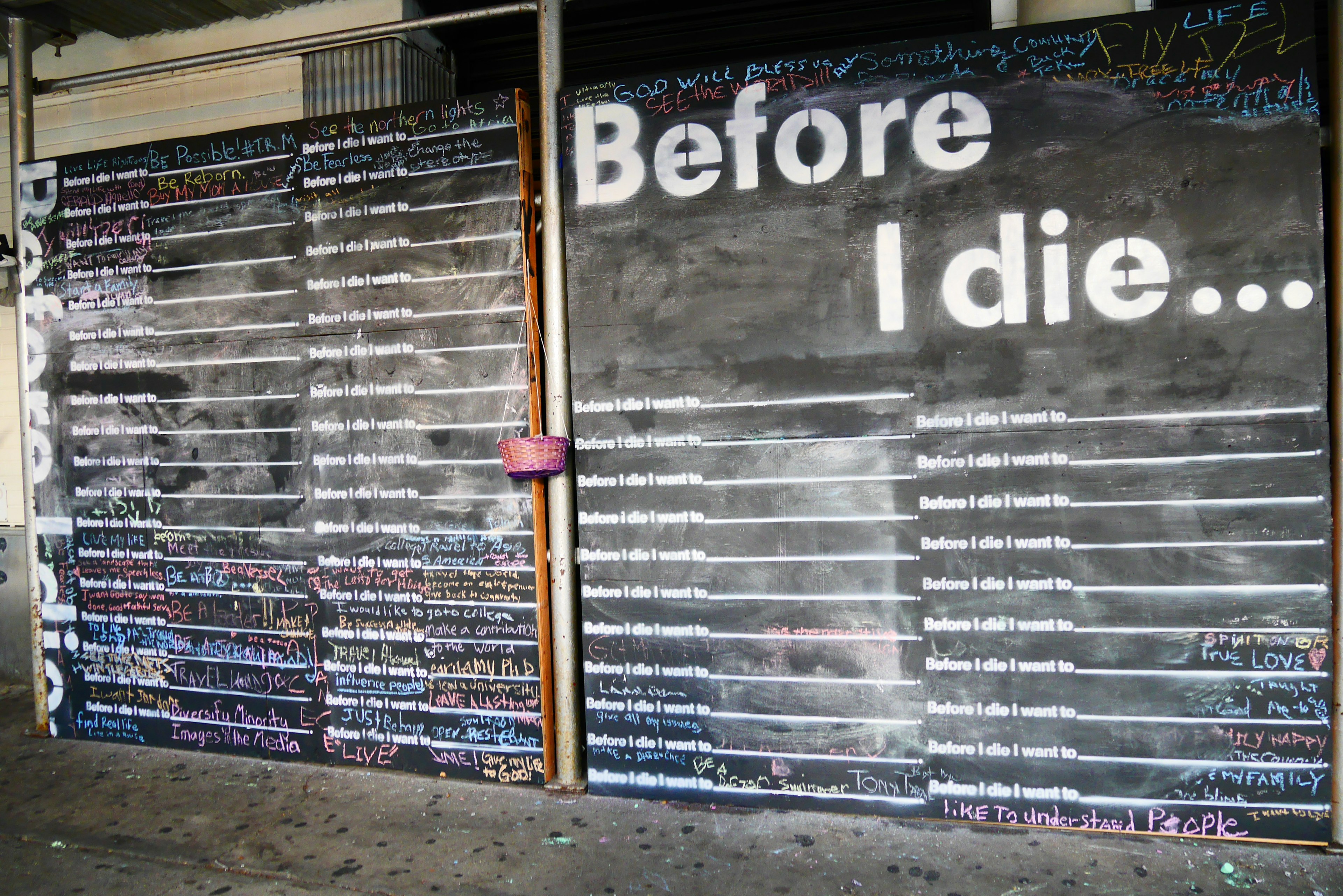 A chalkboard wall featuring the phrase Before I die... with blank lines for messages