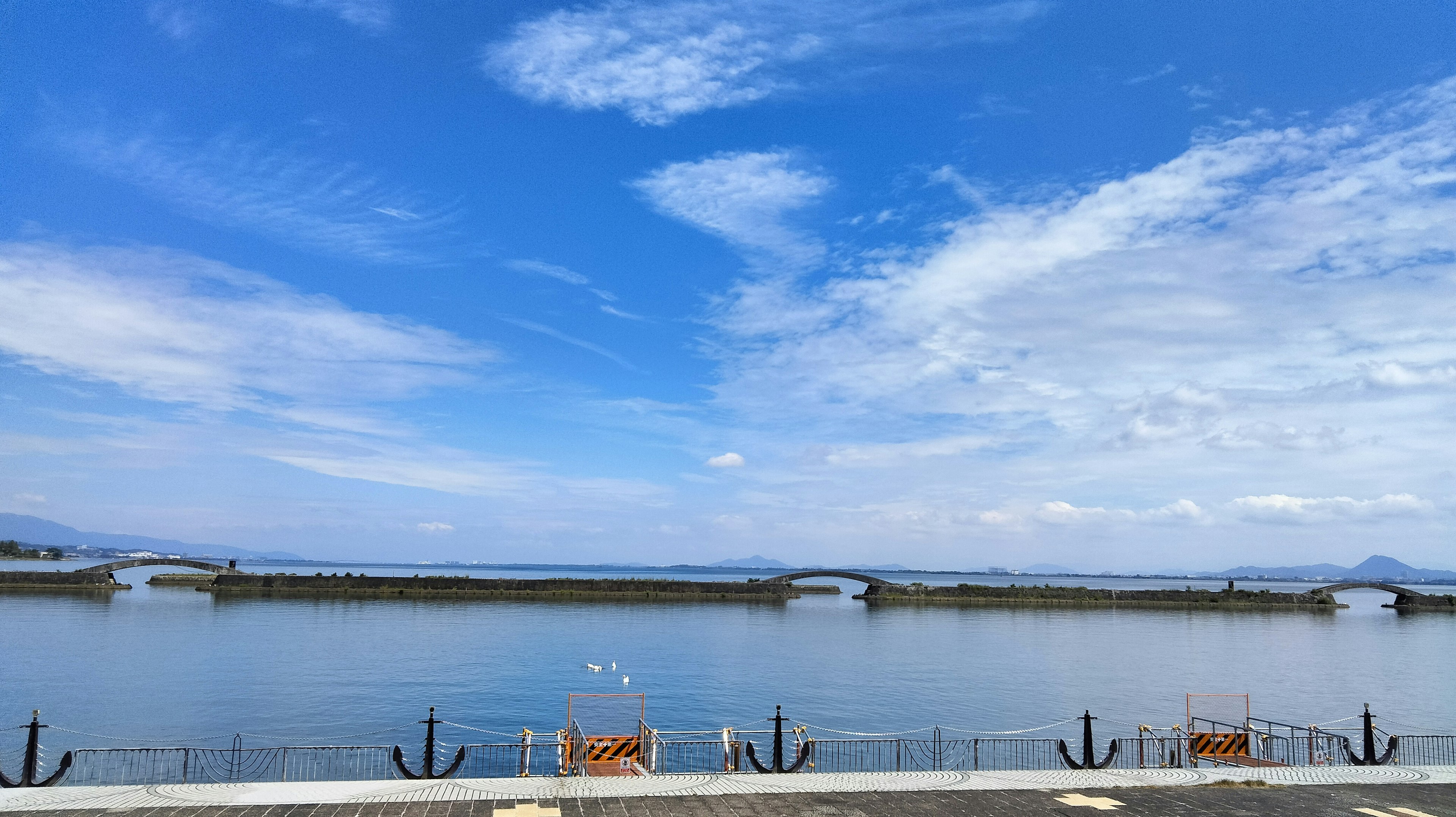 Vista panoramica di cielo blu e acqua con ponti e panchine