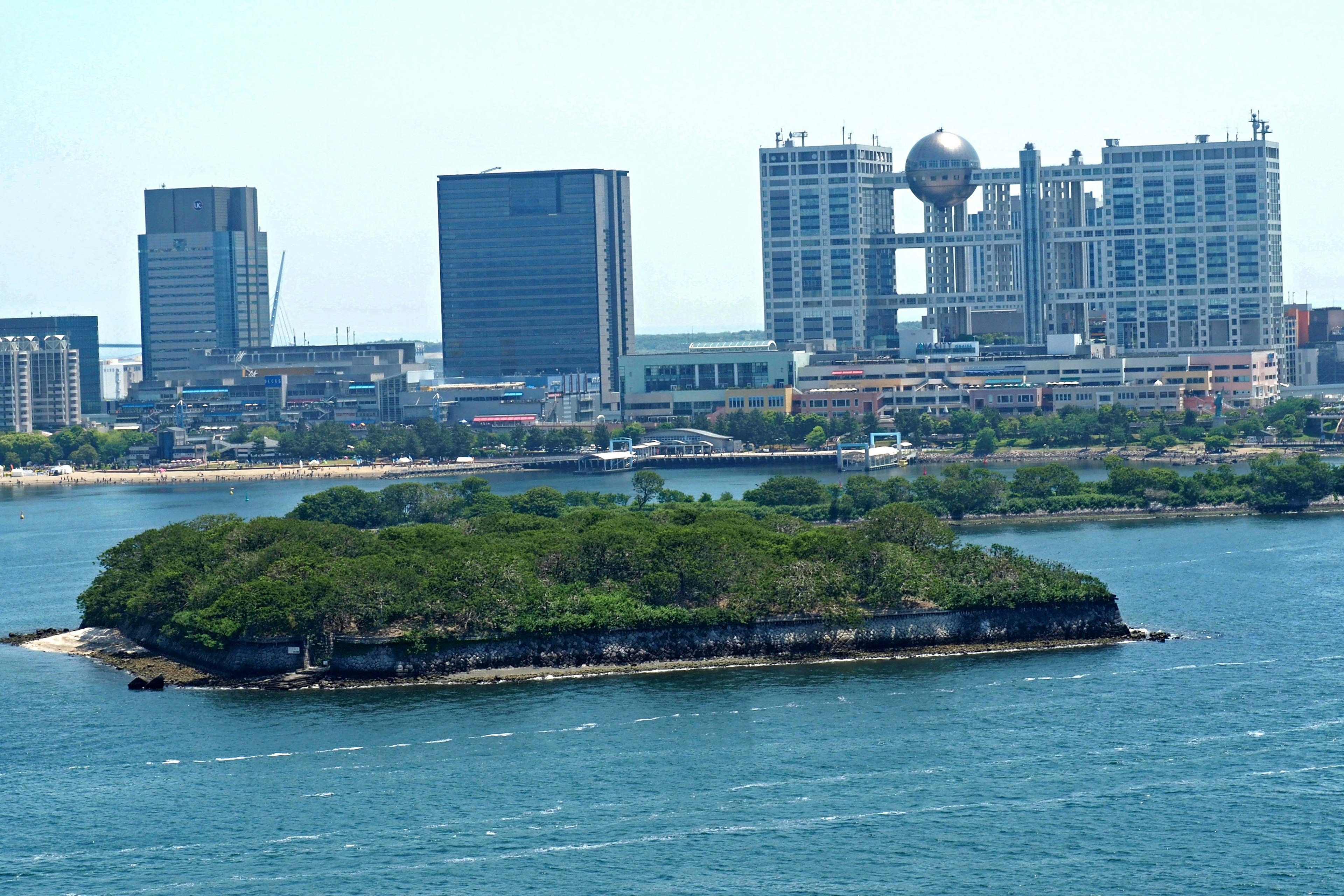 A lush green island with modern skyscrapers in the background