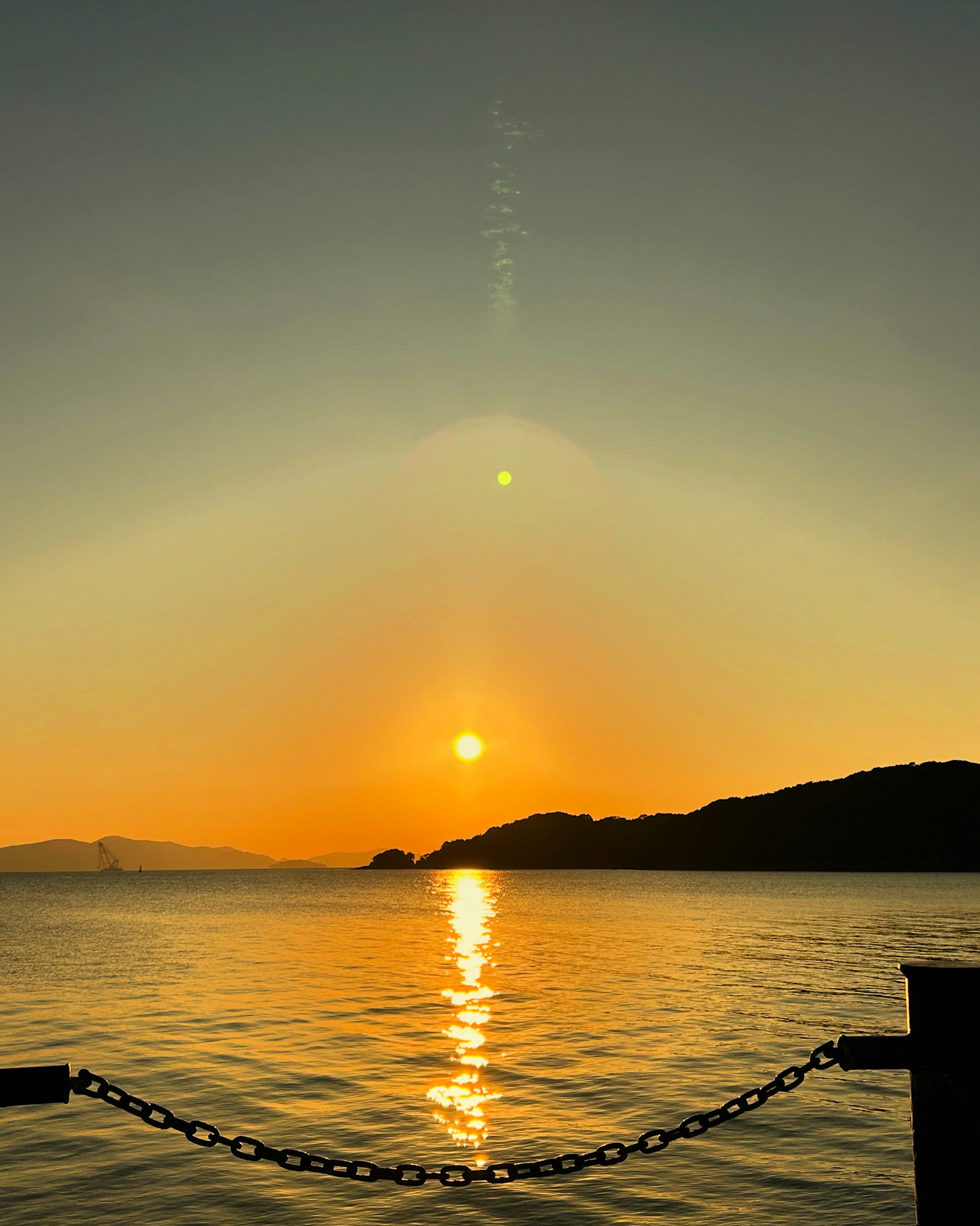 夕日が水面に反射している美しい海の風景と山のシルエット