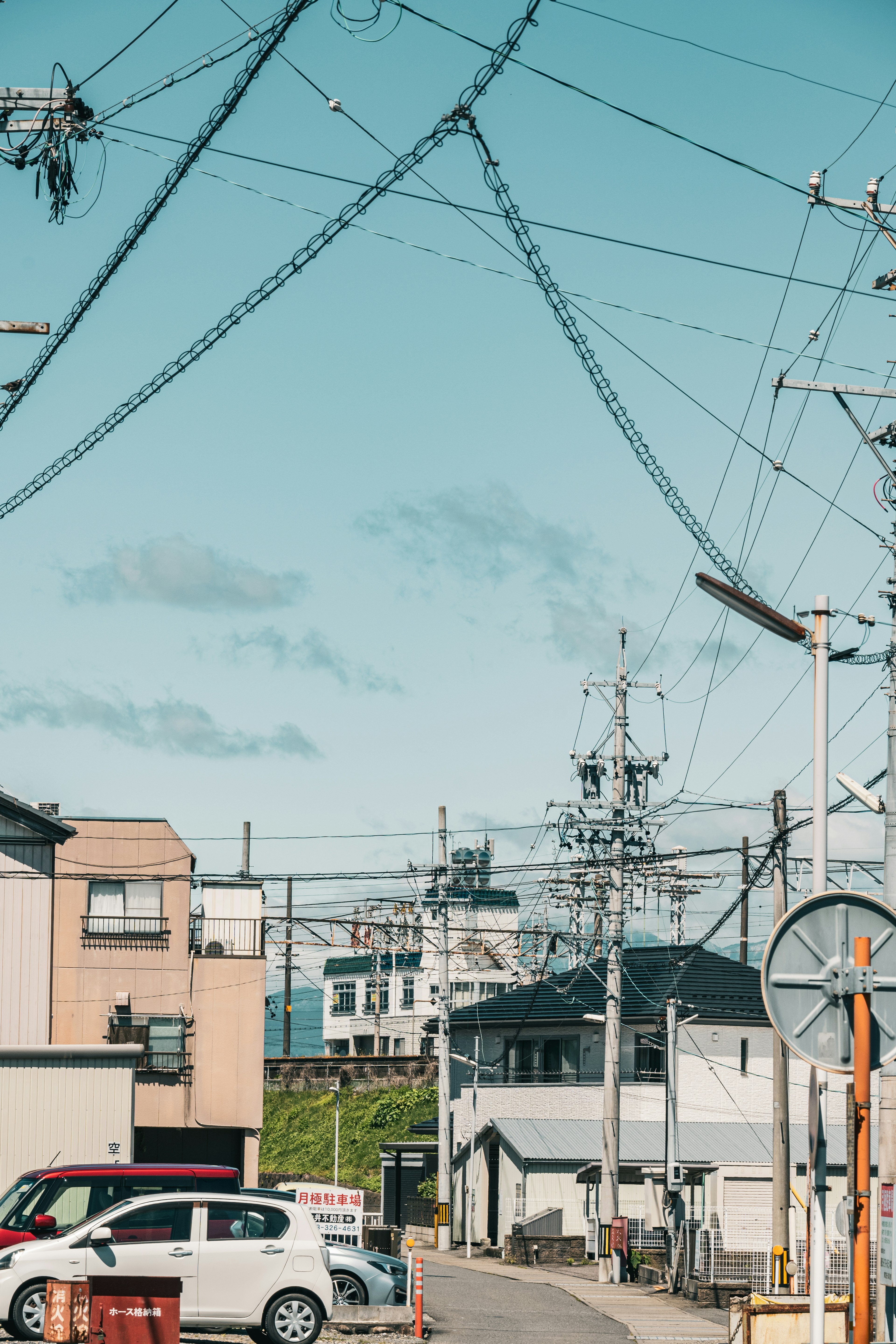 Urban landscape with intersecting power lines and utility poles under a blue sky