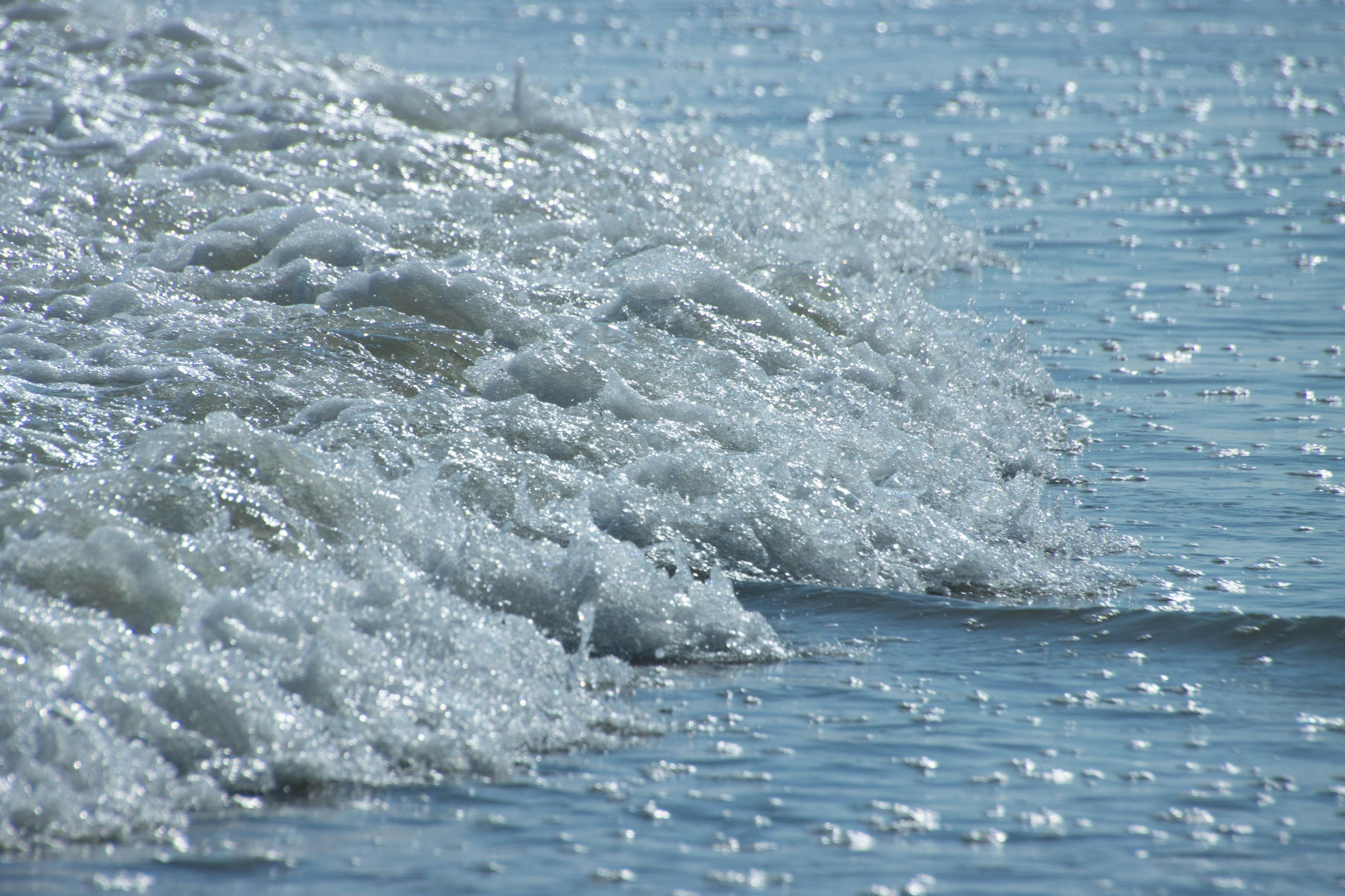 Waves crashing on a blue sea with sparkling bubbles and reflections