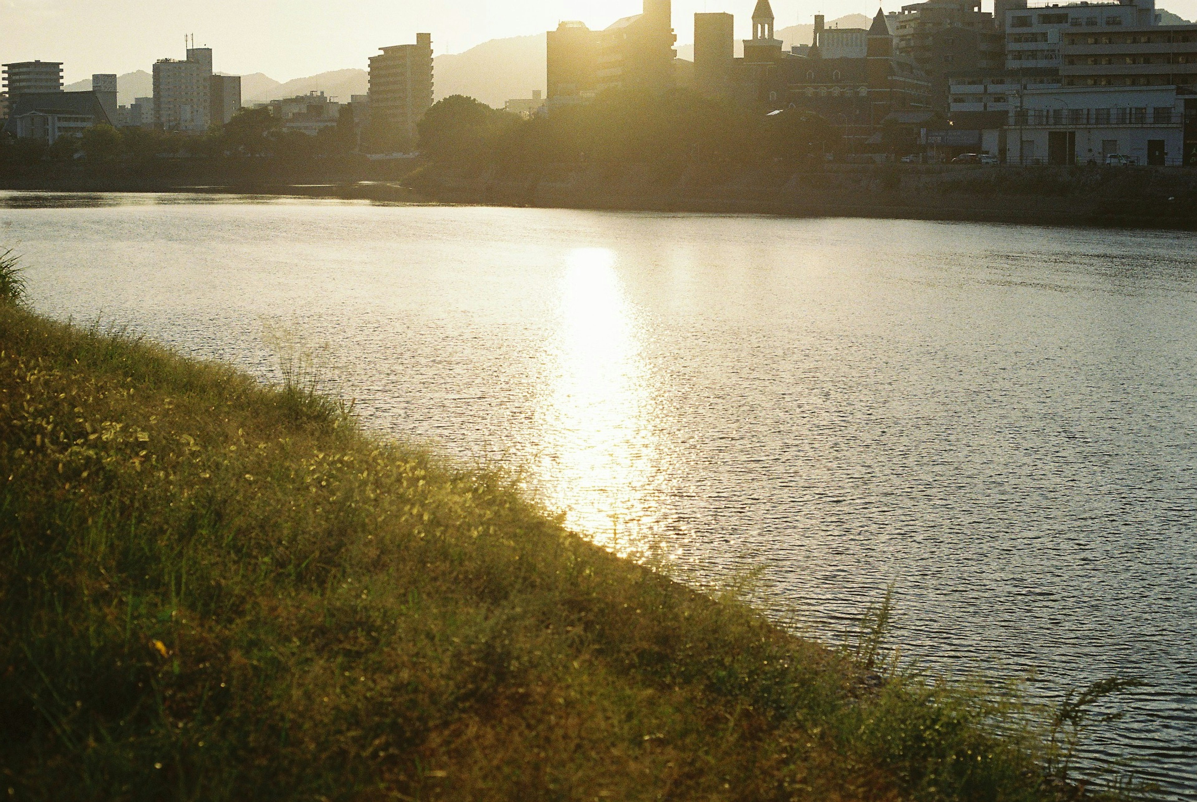 Scenic view of sunset reflecting on a river with city skyline