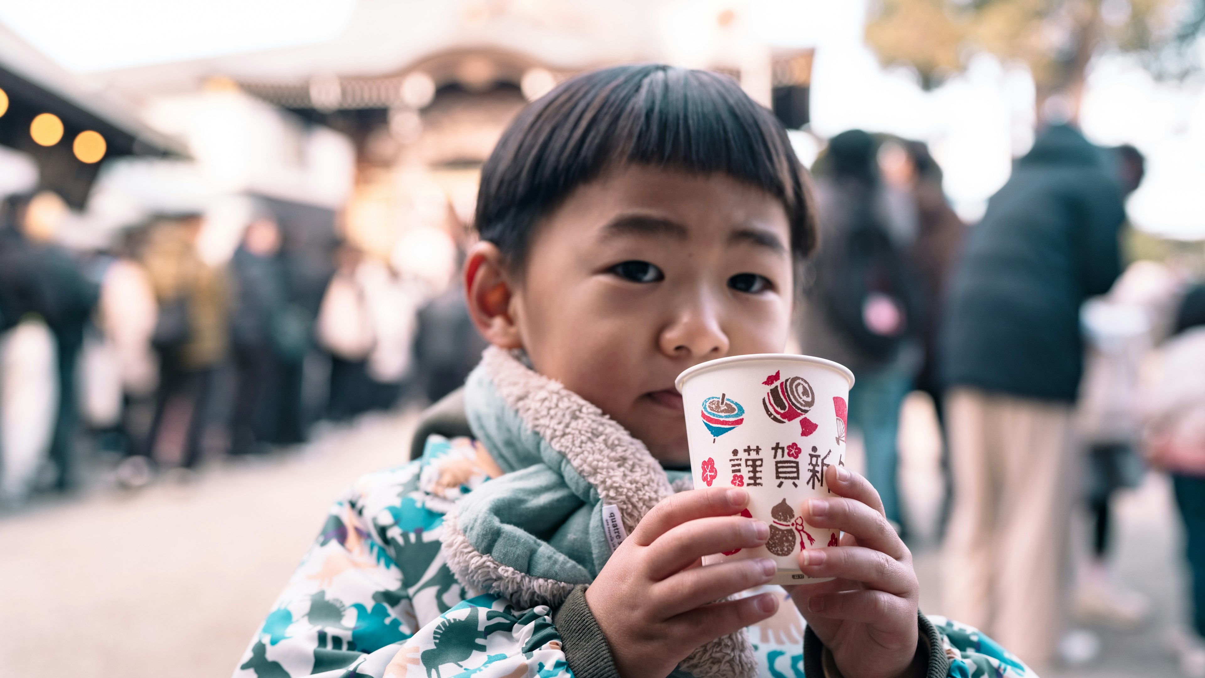 Child holding a drink with people in line in the background