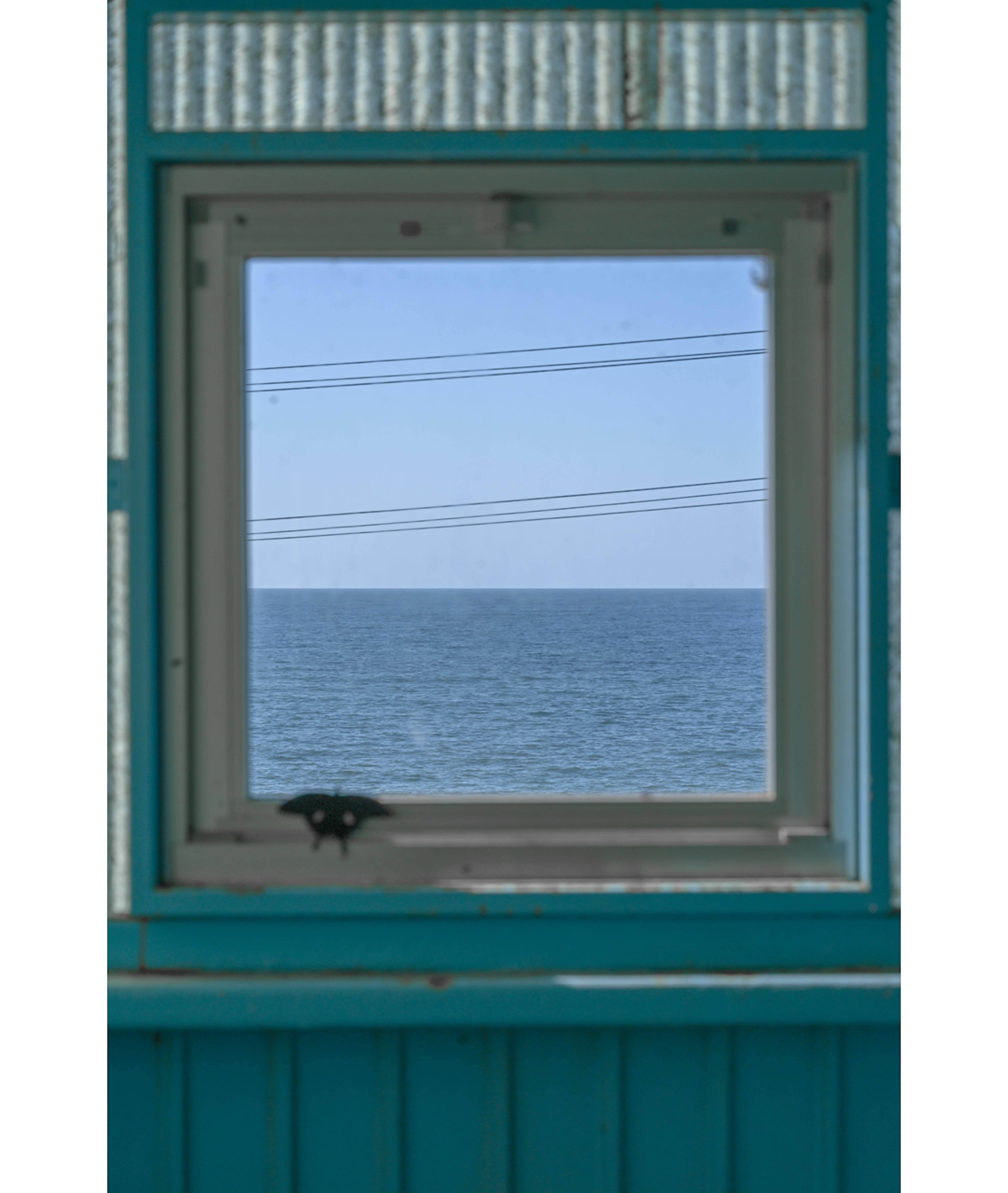 Vista del océano a través de un marco de ventana turquesa