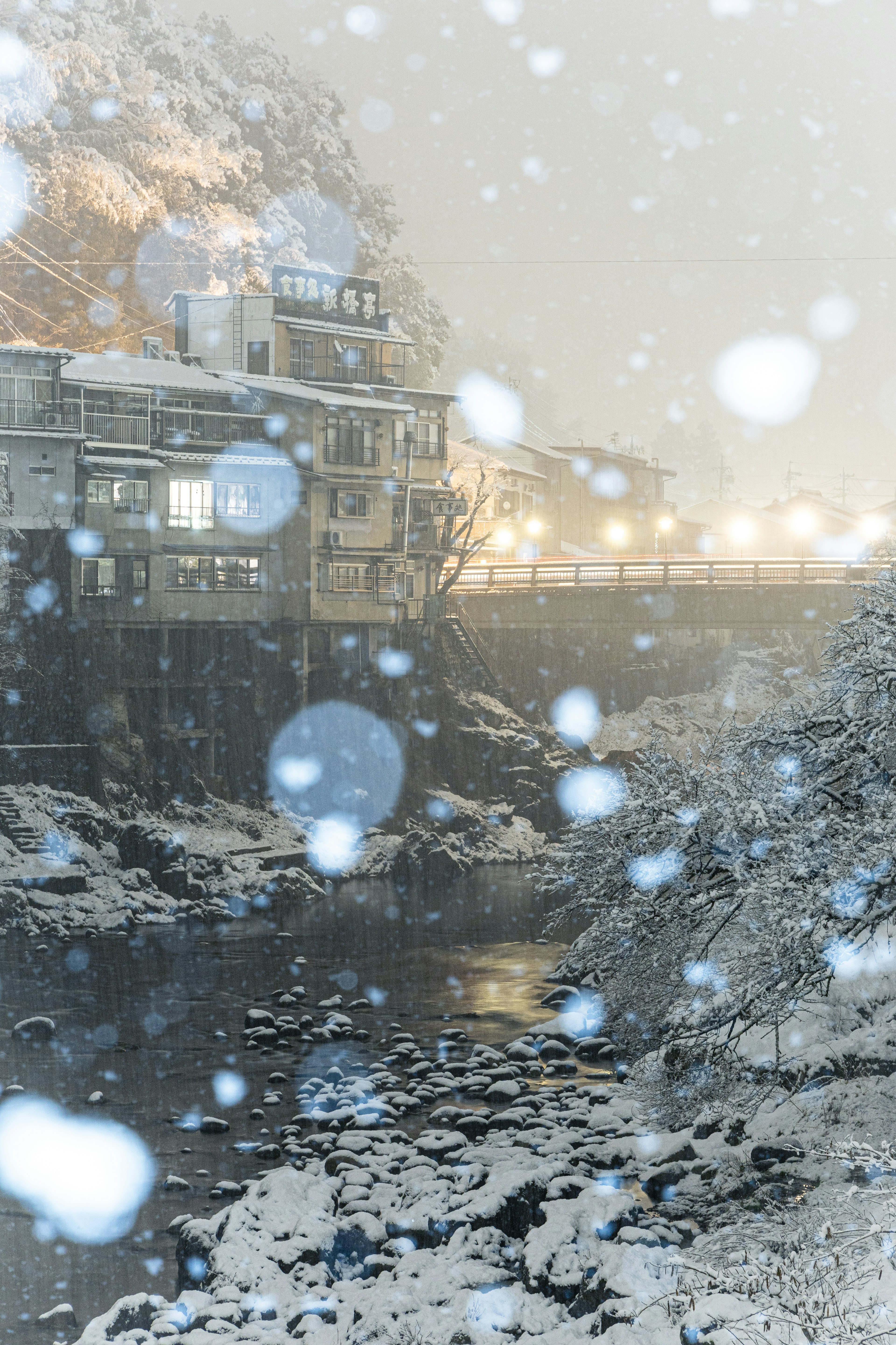 雪の降る夜の川沿いの風景と温泉宿