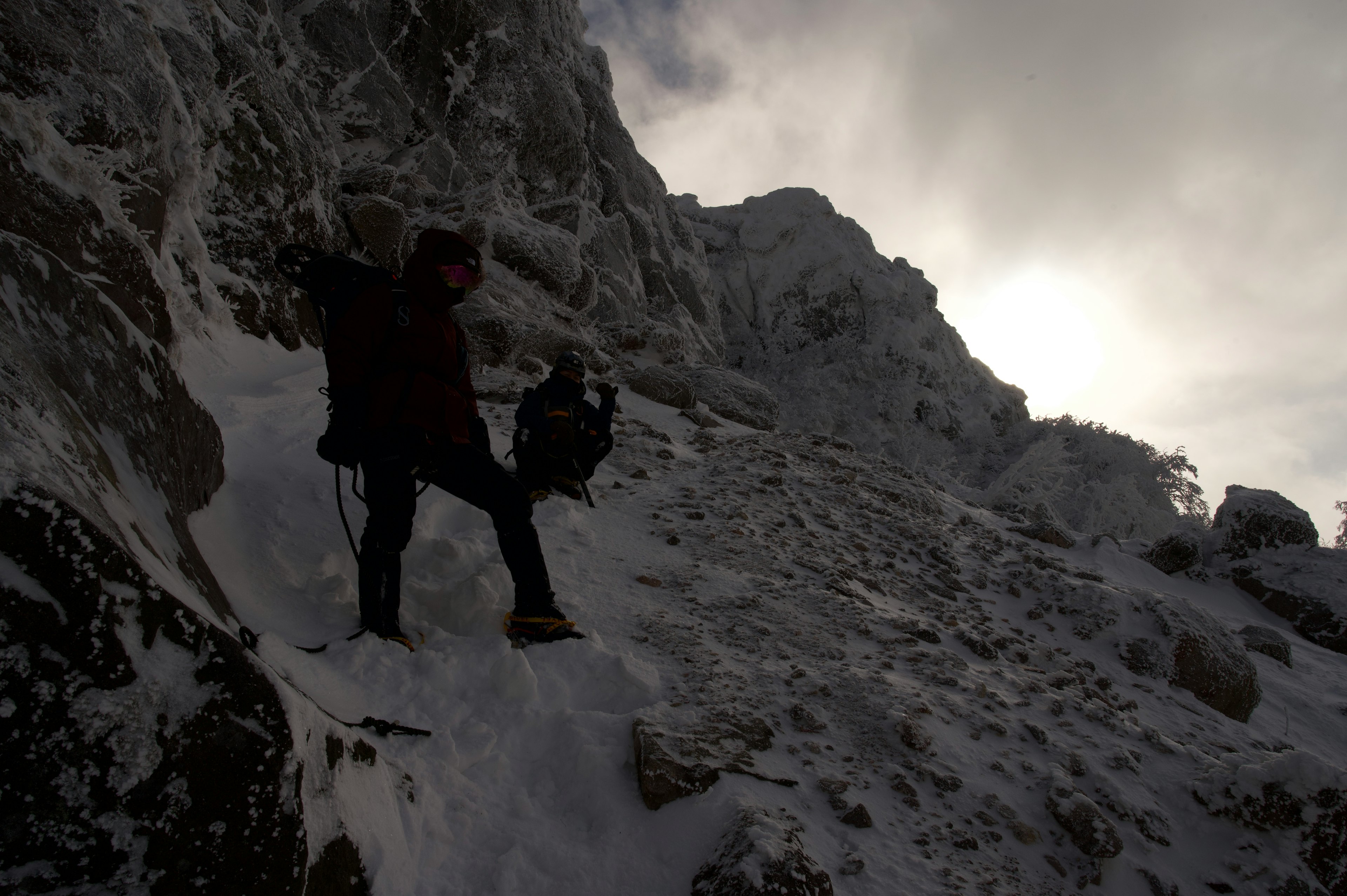 Silhouette de deux grimpeurs montant une montagne enneigée