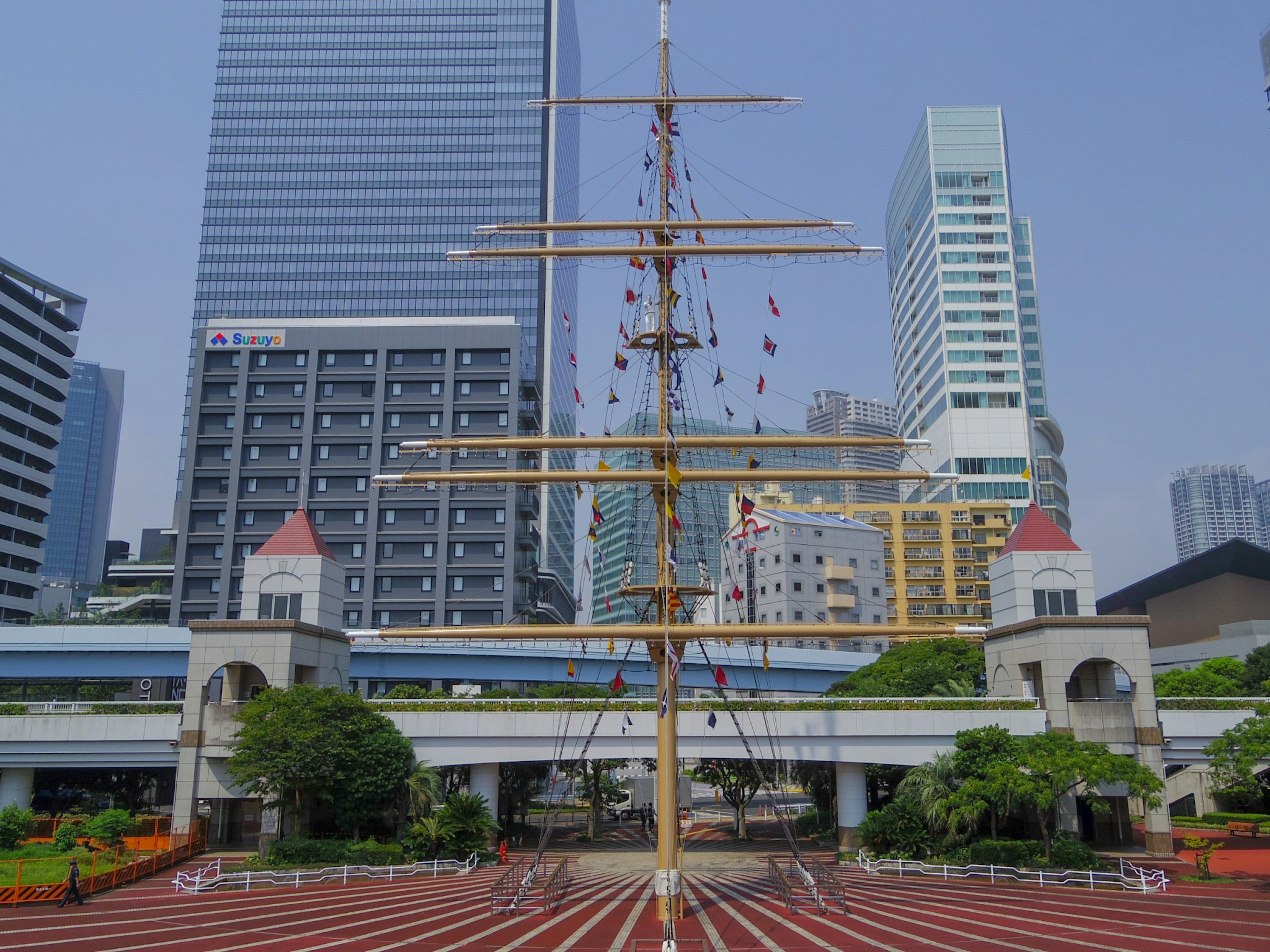 Ship mast surrounded by skyscrapers and greenery