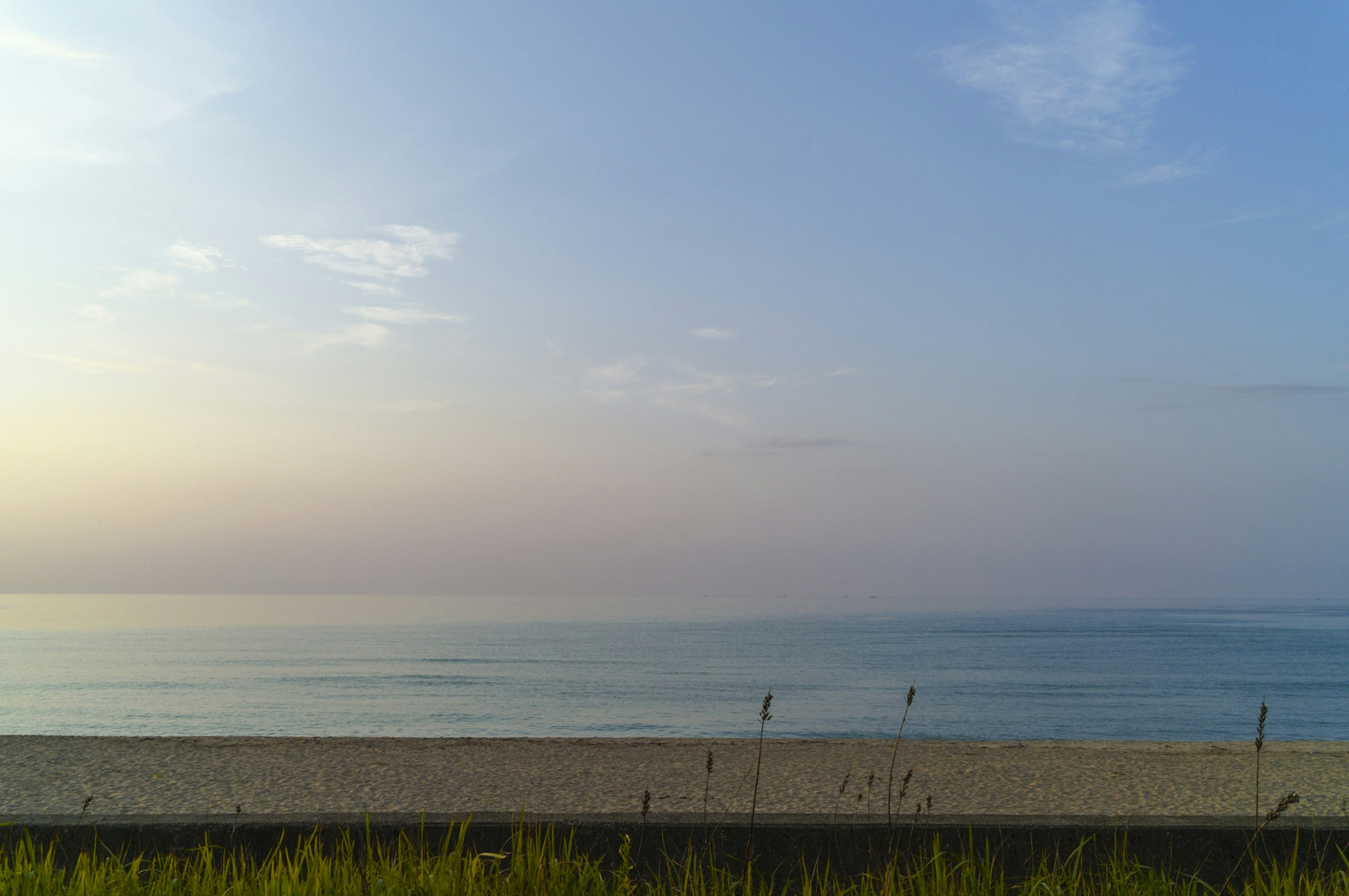 Paisaje de mar tranquilo y playa de arena con tonos de cielo al atardecer