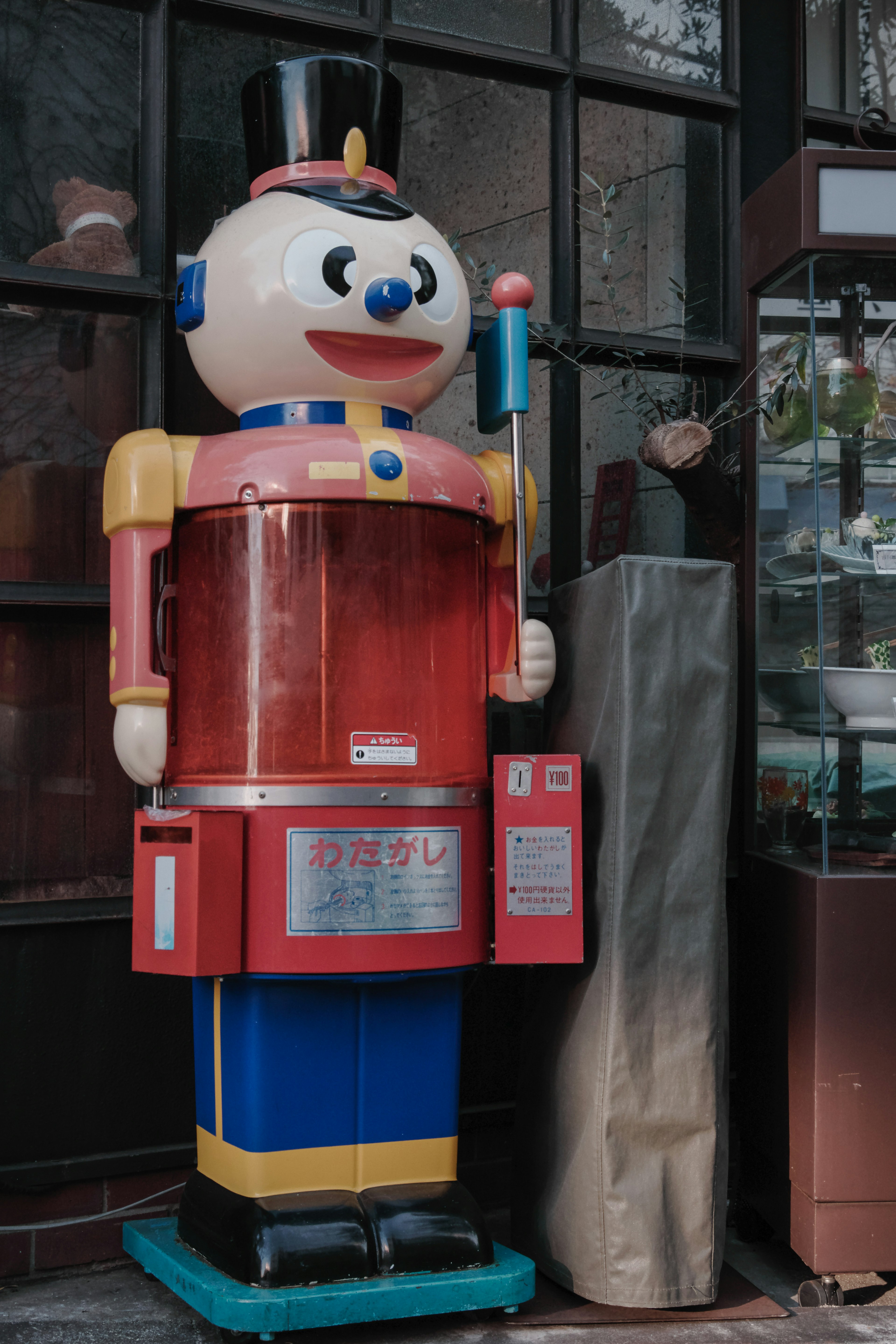 Distributeur automatique en forme de robot coloré devant un magasin