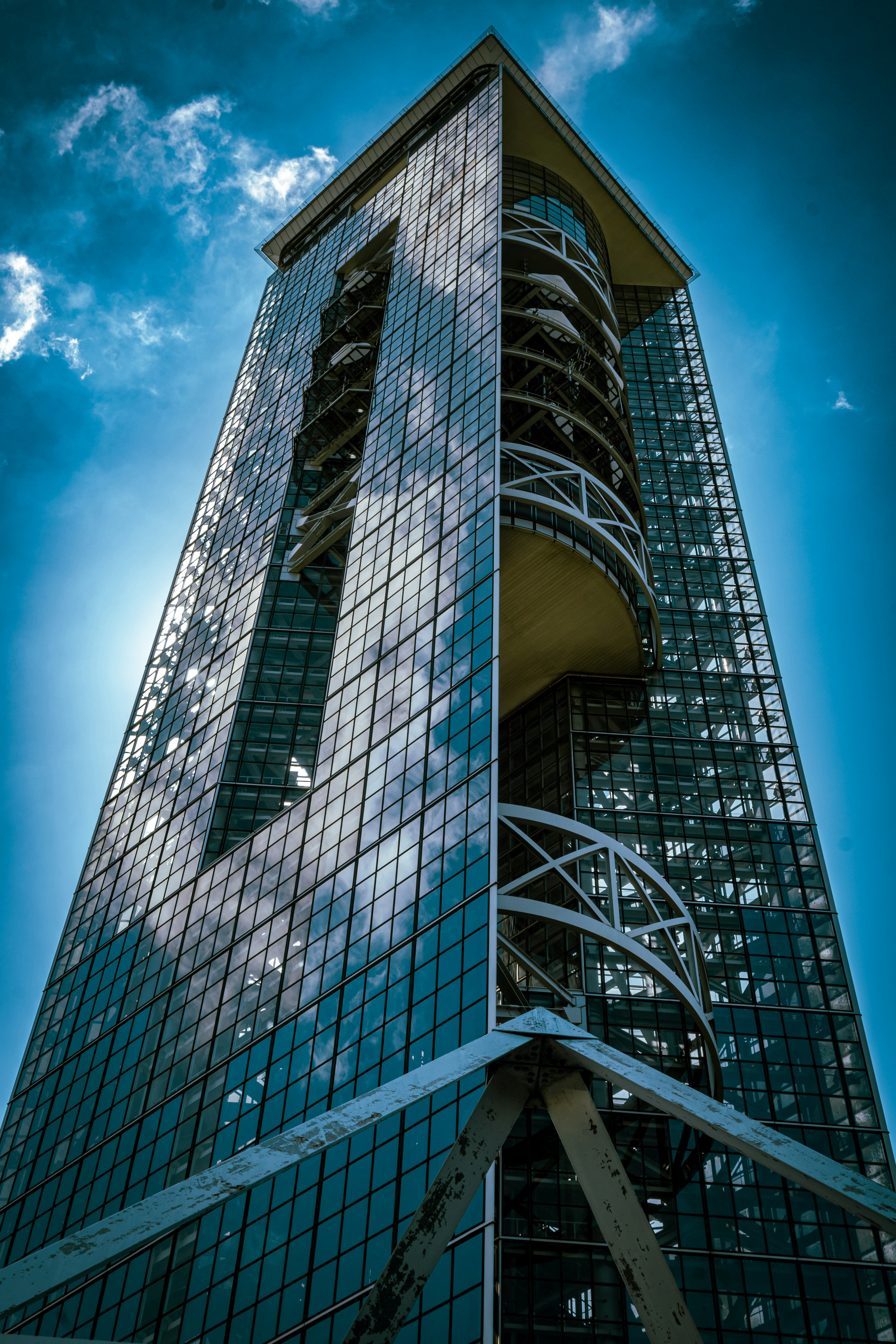 Nahaufnahme eines Wolkenkratzers mit reflektierender Glasfassade und rundem Balkon