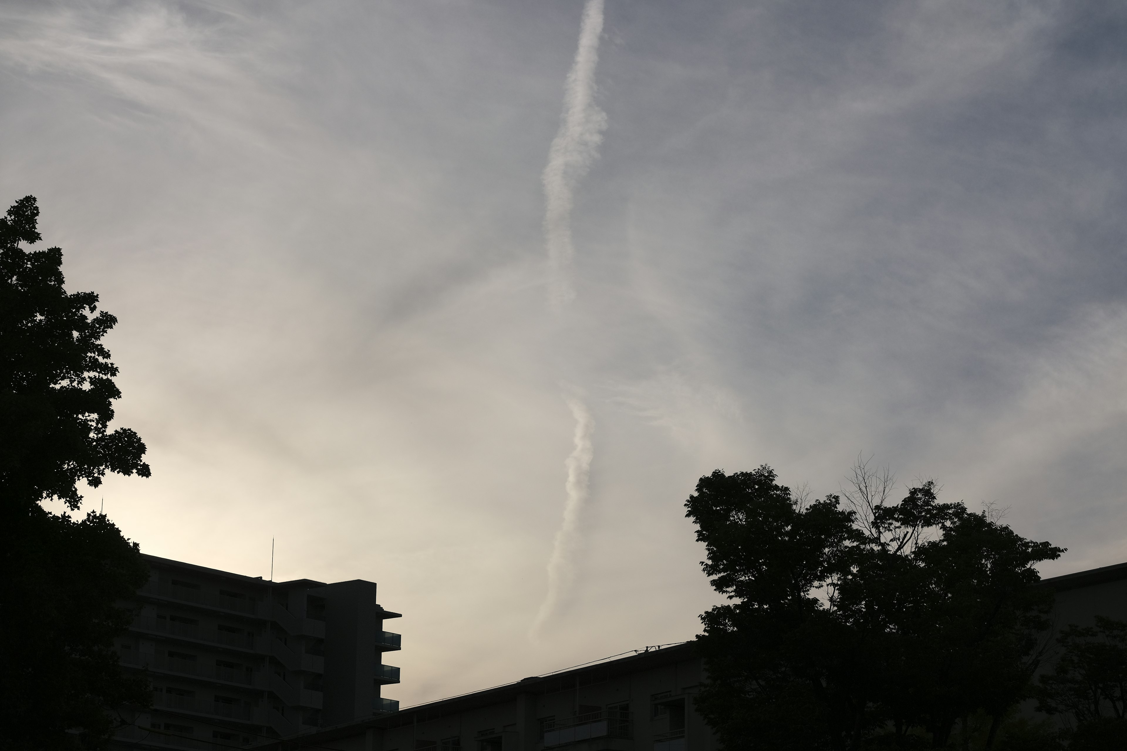 空に浮かぶ雲の帯と建物のシルエット