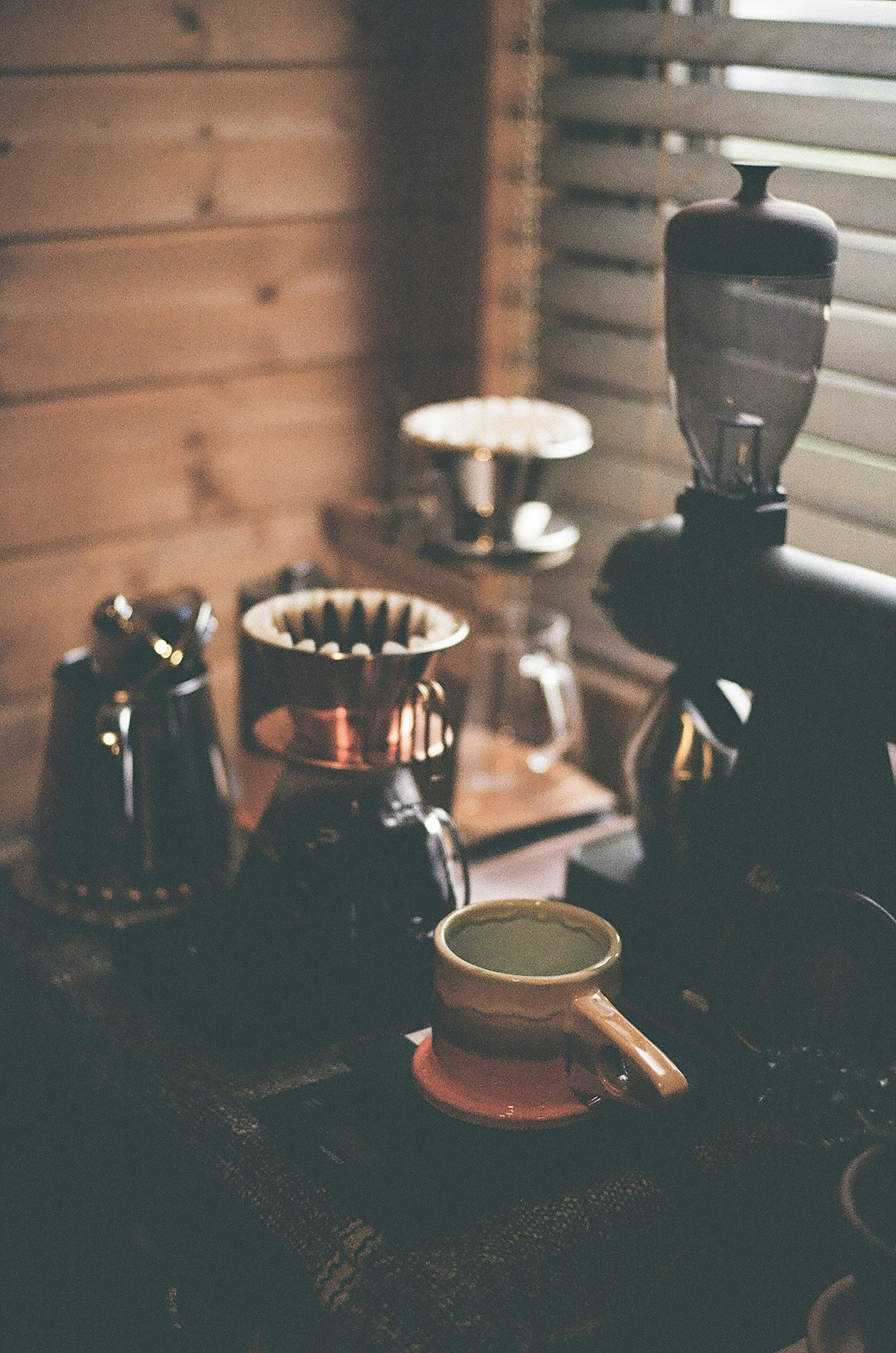 Stillleben von Kaffeeausrüstung und Tasse vor einer Holzwand