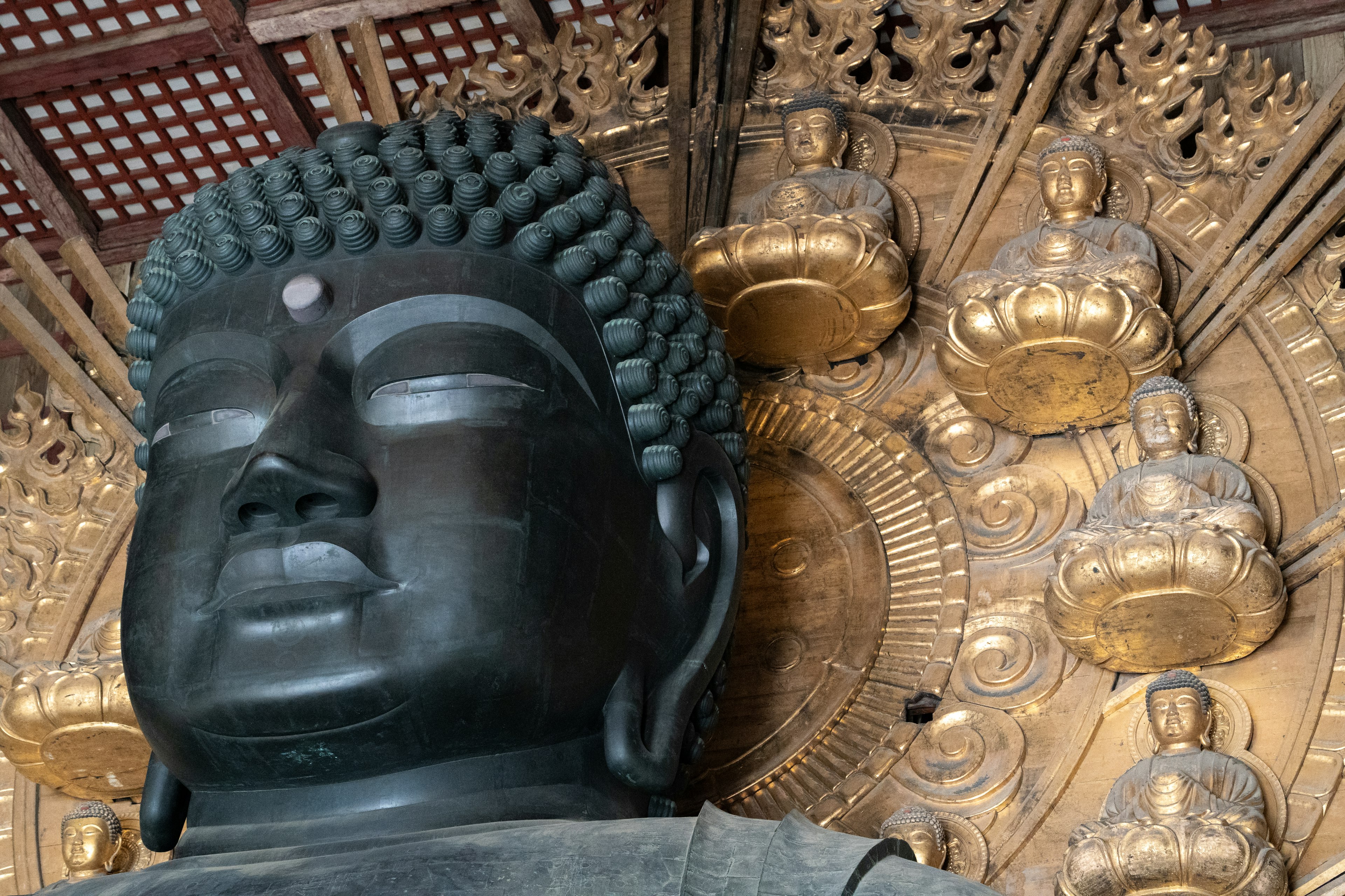 Nahaufnahme einer Buddha-Statue mit goldenen Figuren im Hintergrund