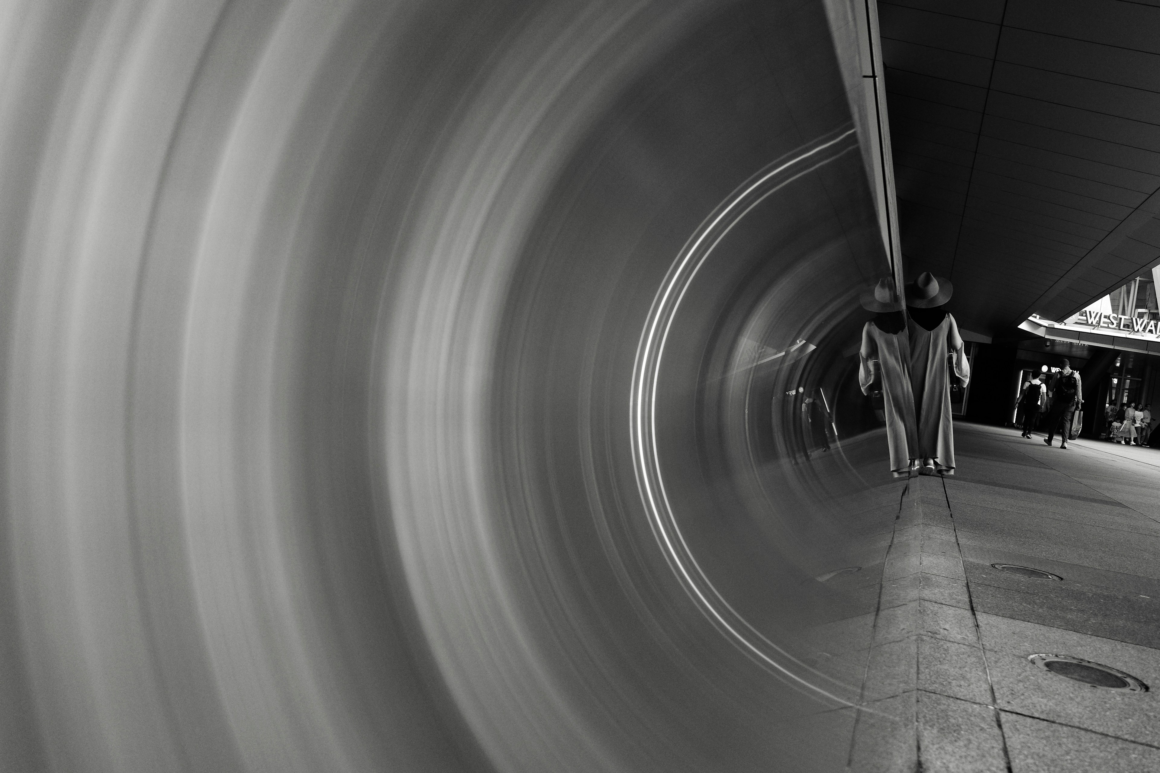 Dynamic black and white image of people walking through a tunnel