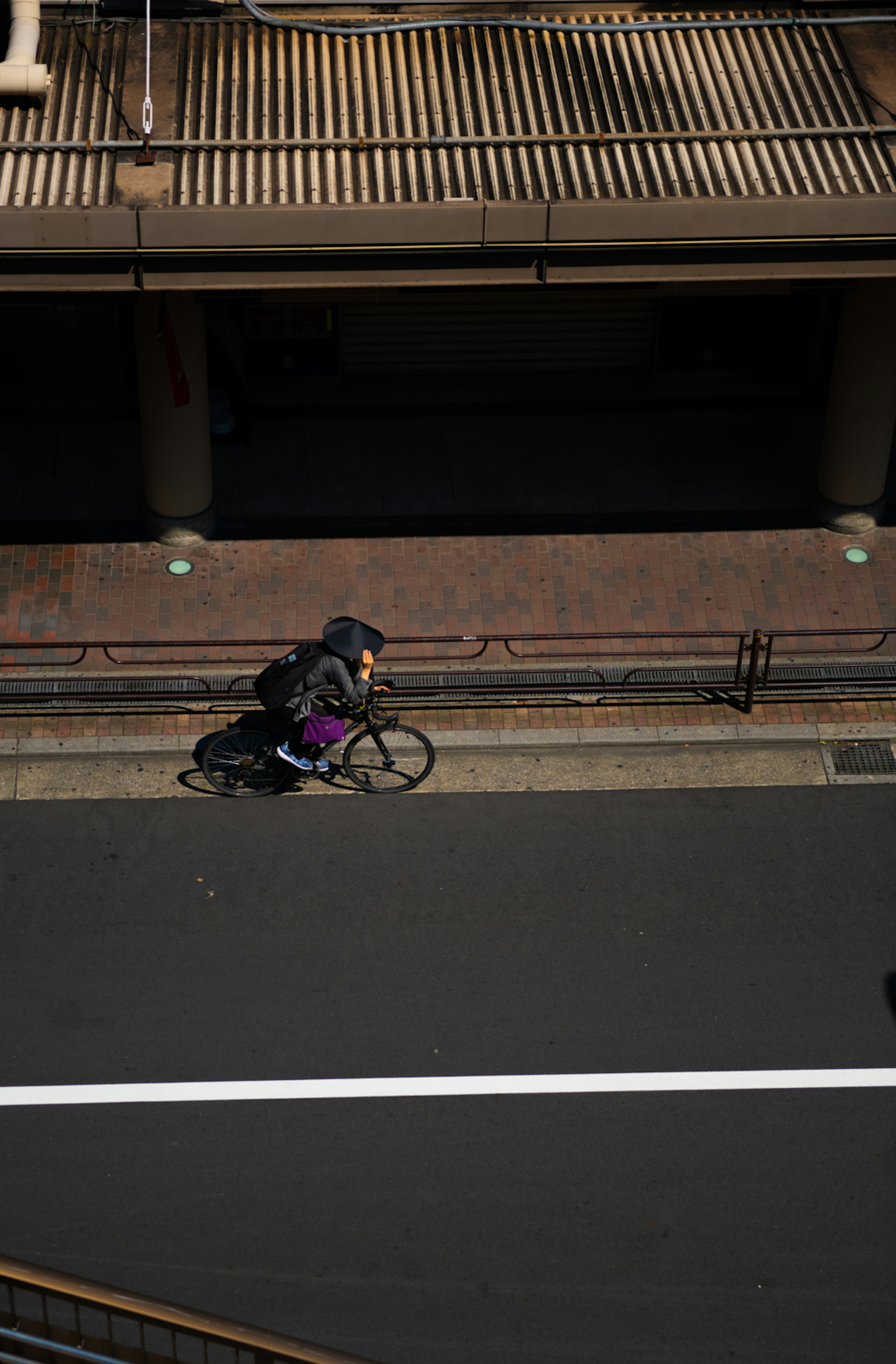 A person riding a bicycle on a road captured from above