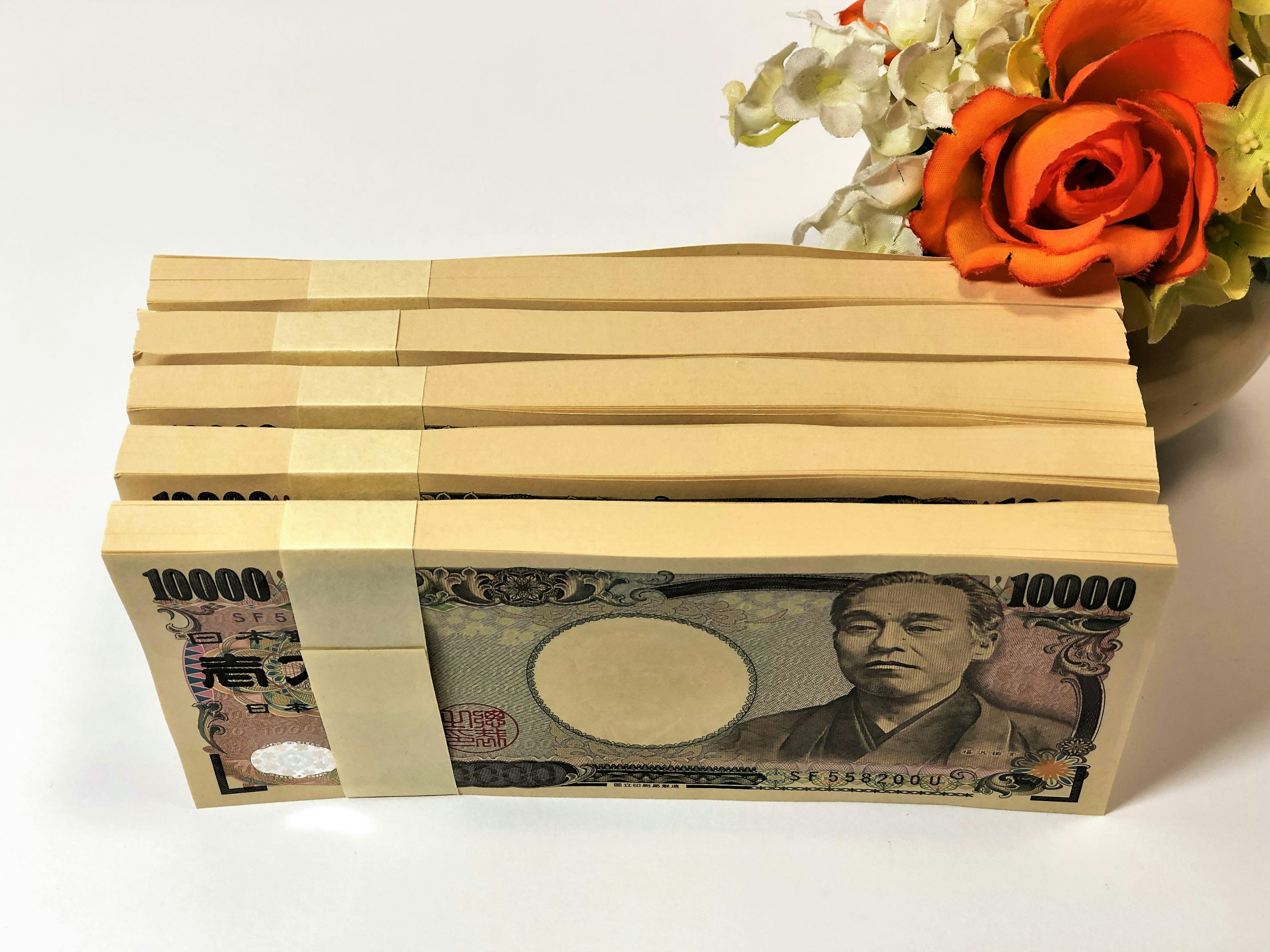 Pile de billets japonais de 10 000 yens avec une rose orange