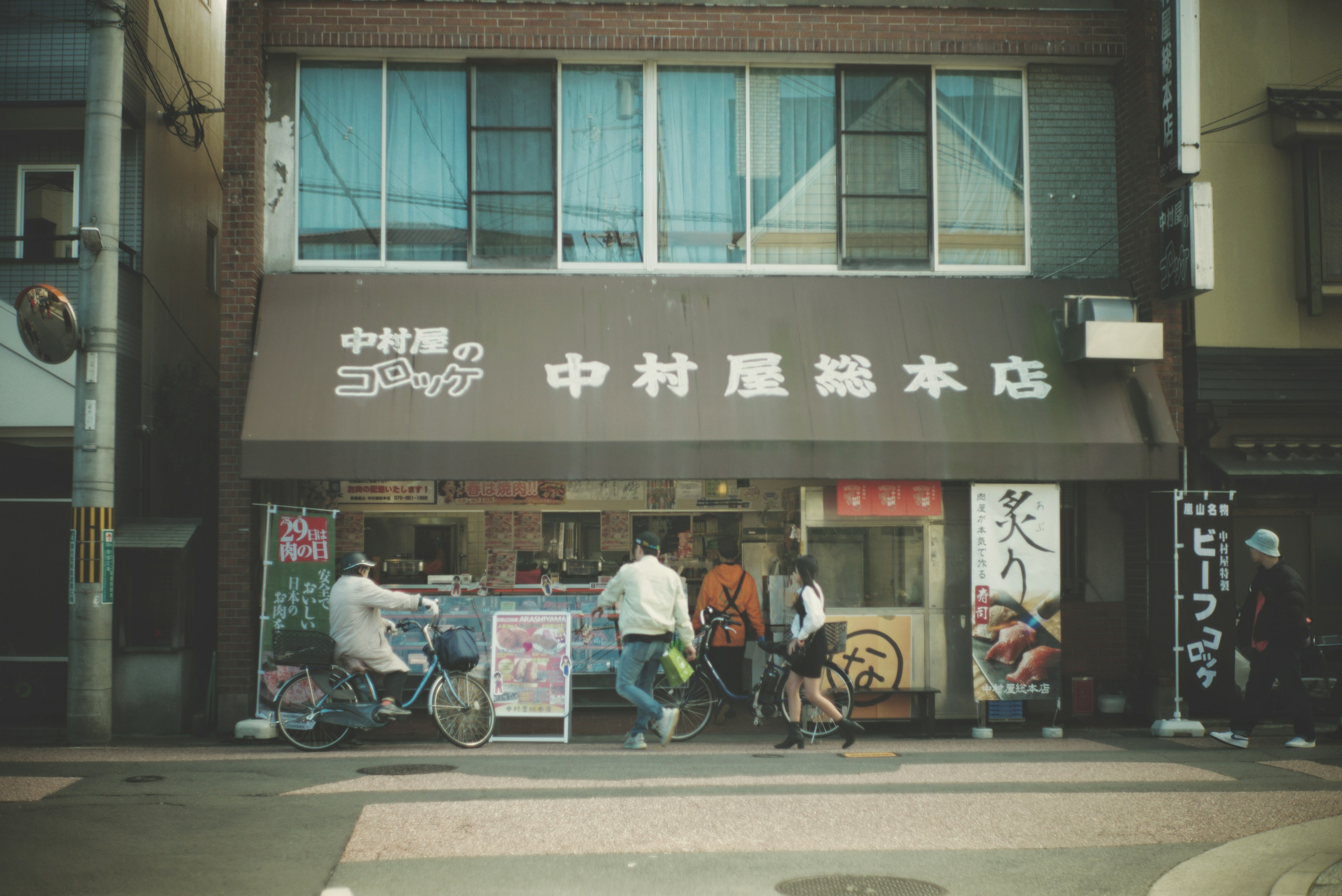 Facade of Nakamuraya shop with people riding bicycles