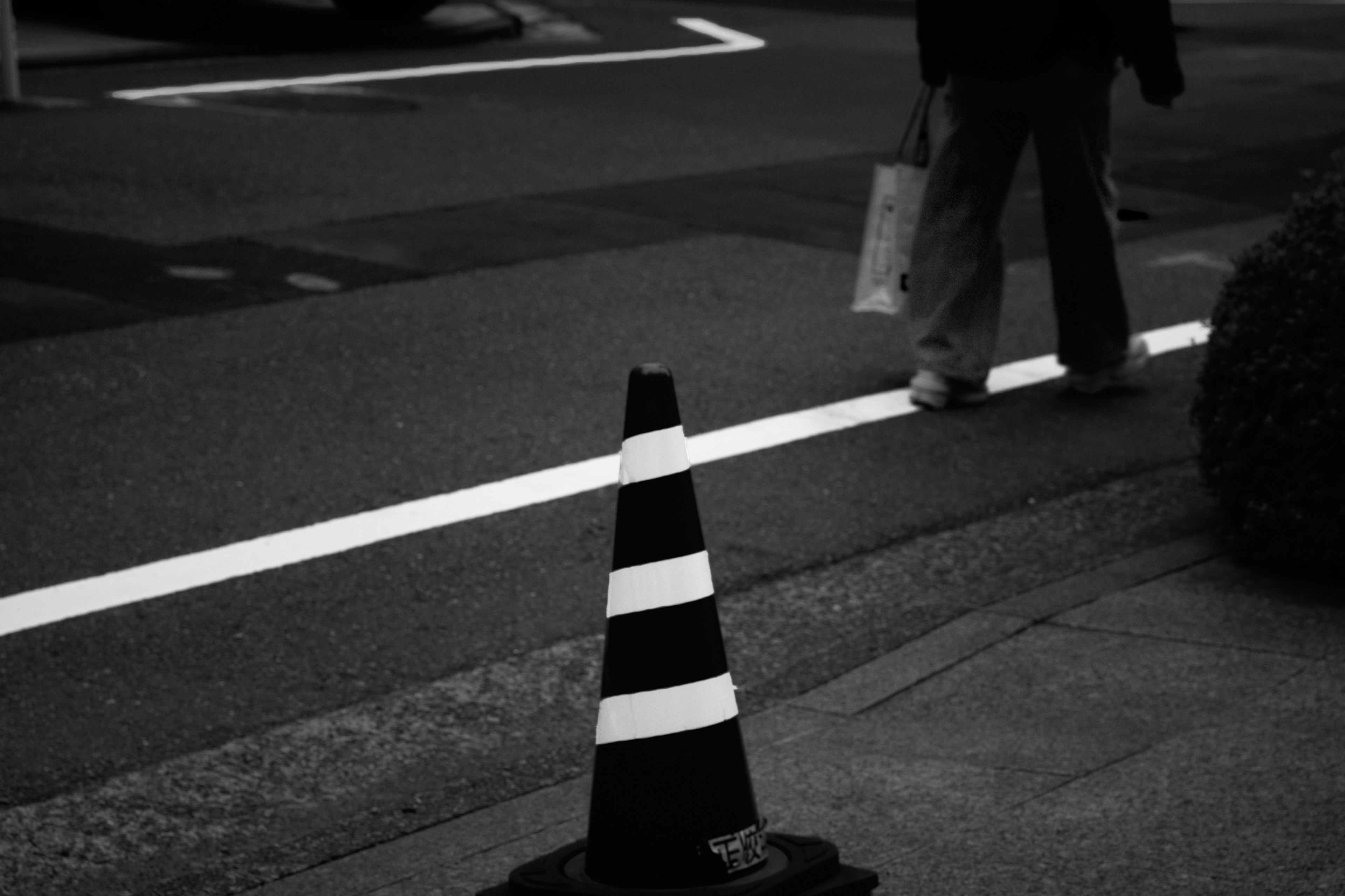 Una persona che cammina vicino a un cono stradale e a una linea bianca sulla strada