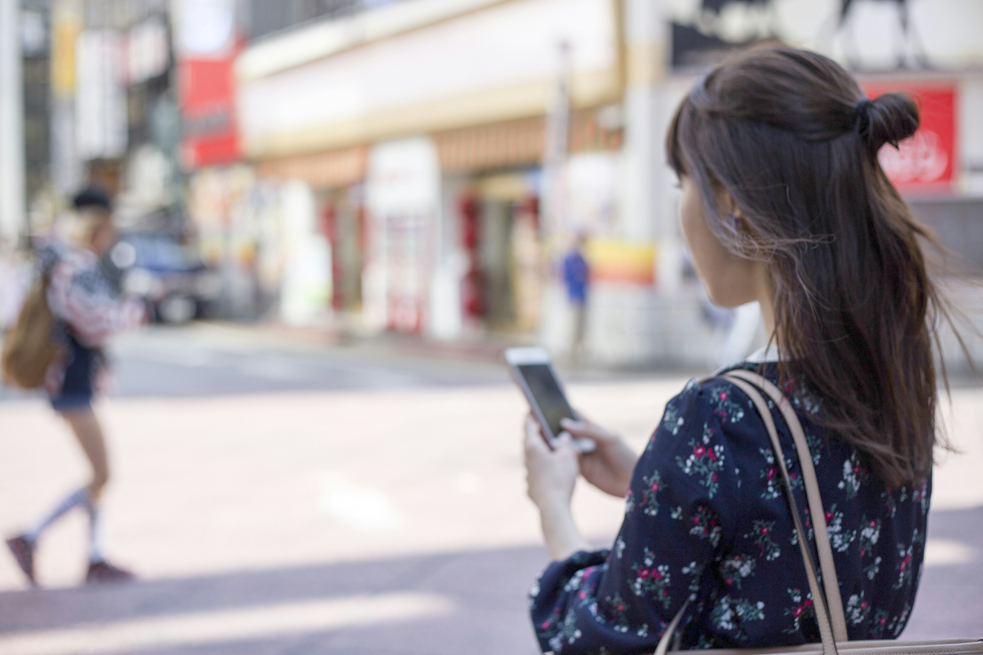 Mujer joven usando un teléfono inteligente en una esquina de la calle