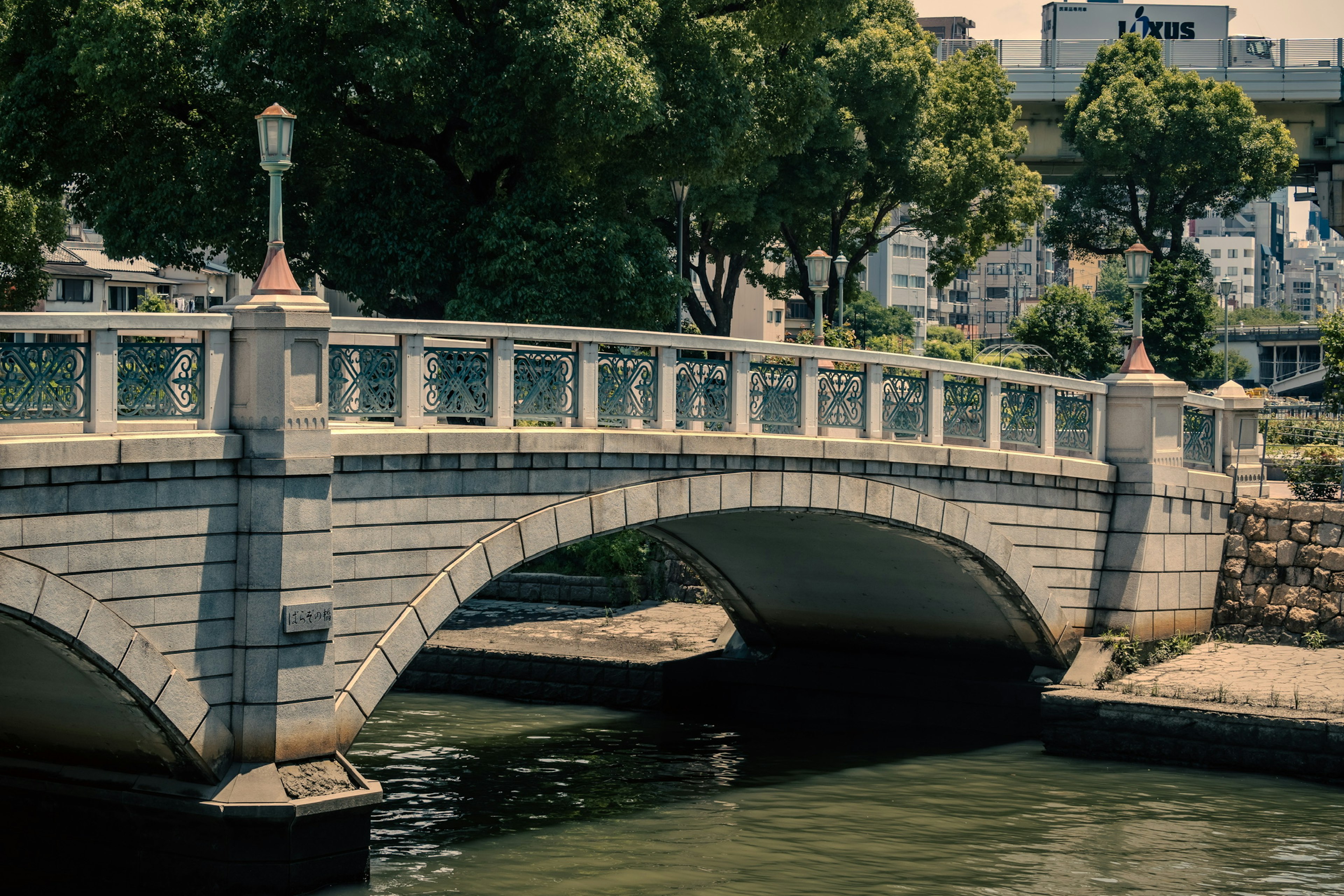 河上的石拱橋，周圍綠樹成蔭，水面平靜