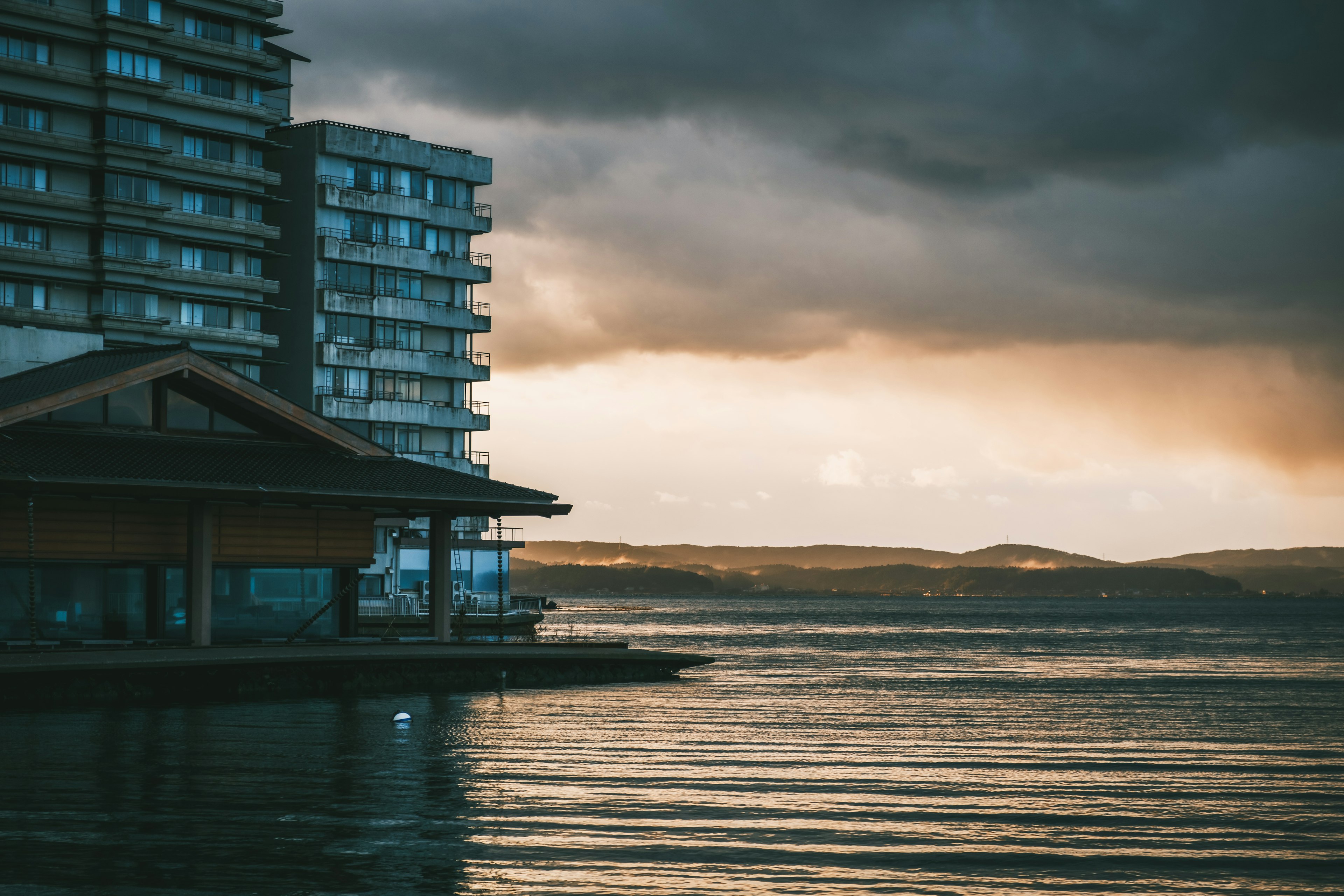 Edificio moderno junto al agua tranquila con cielo nublado