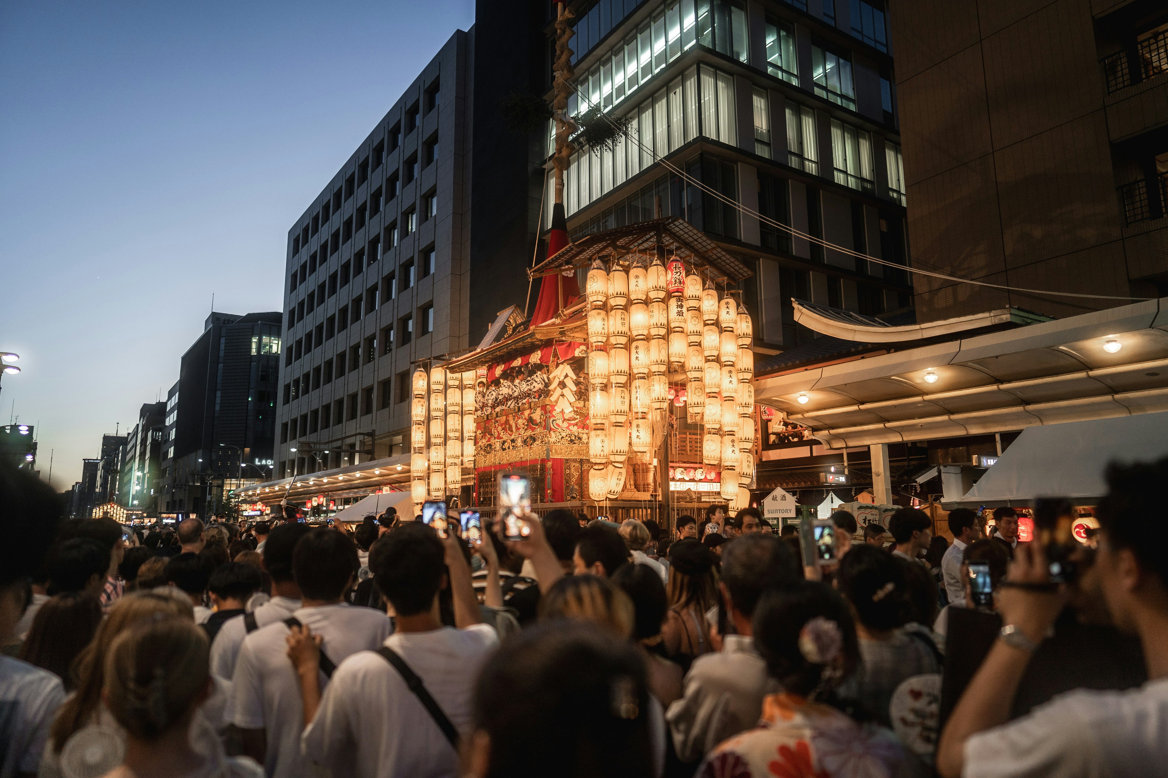 Crowd at a festival with illuminated float during twilight