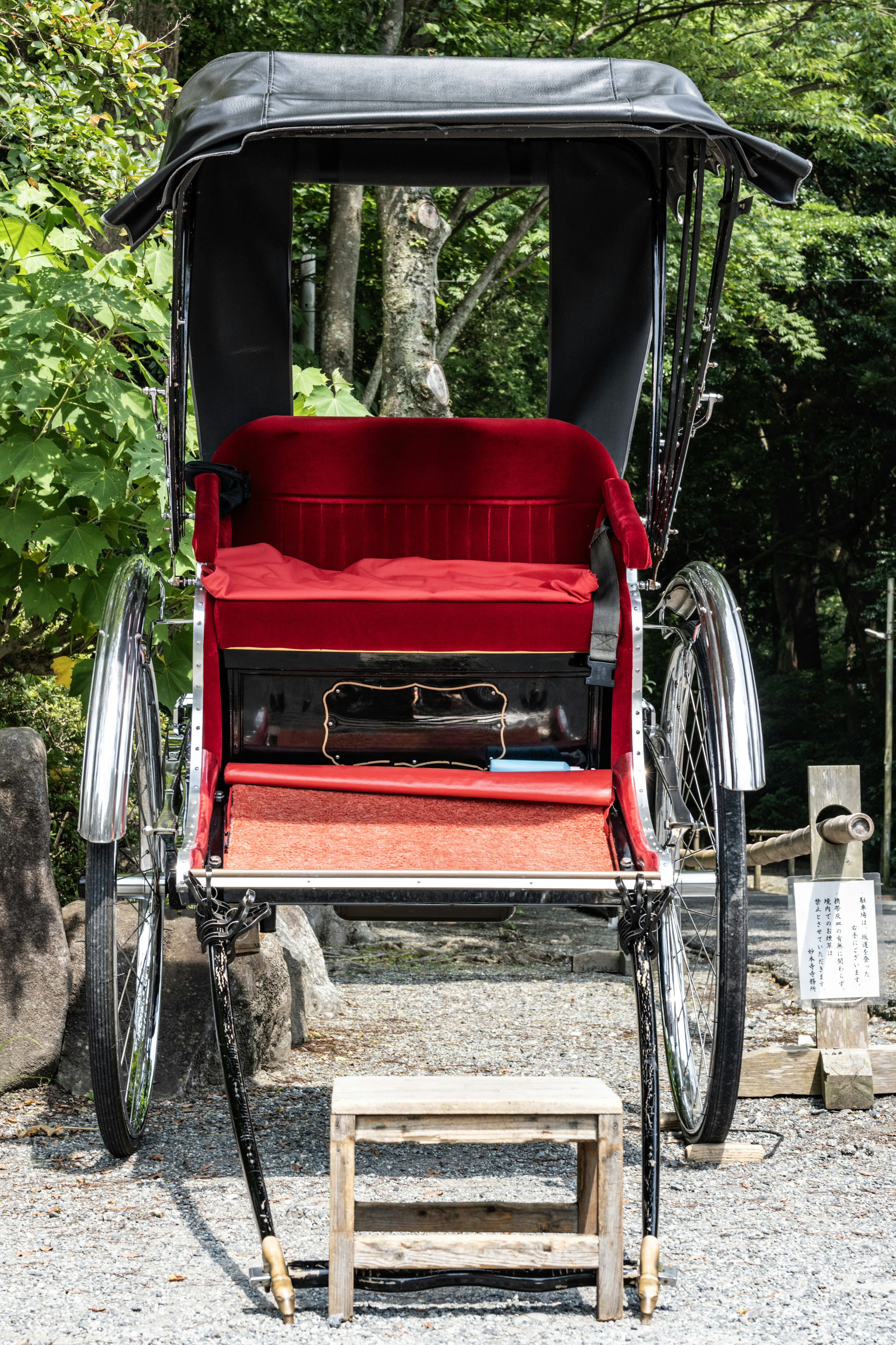 Vista trasera de un rickshaw con cojines rojos y un escalón de madera