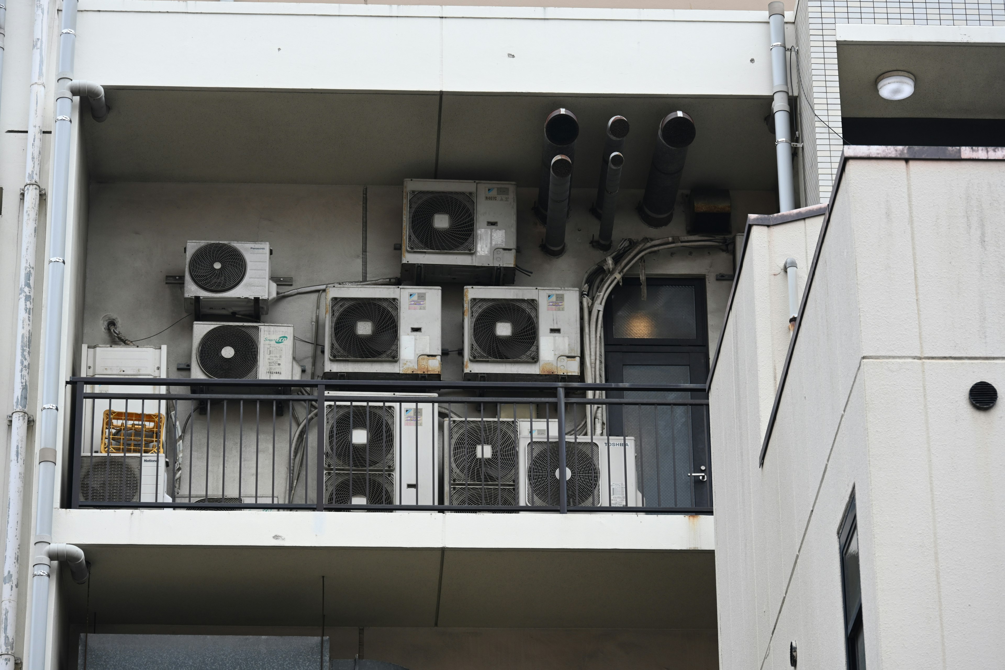 Multiple air conditioning units and pipes on a balcony