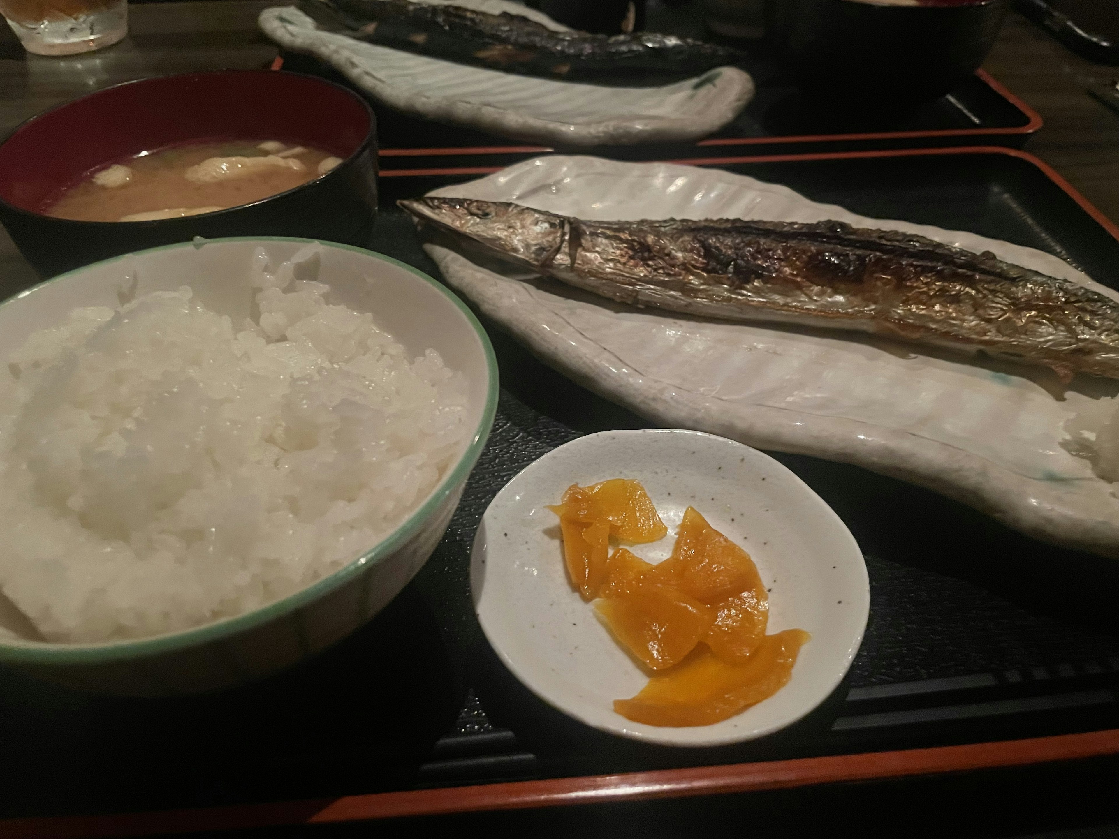 Grilled fish served with rice miso soup and pickles on a white plate