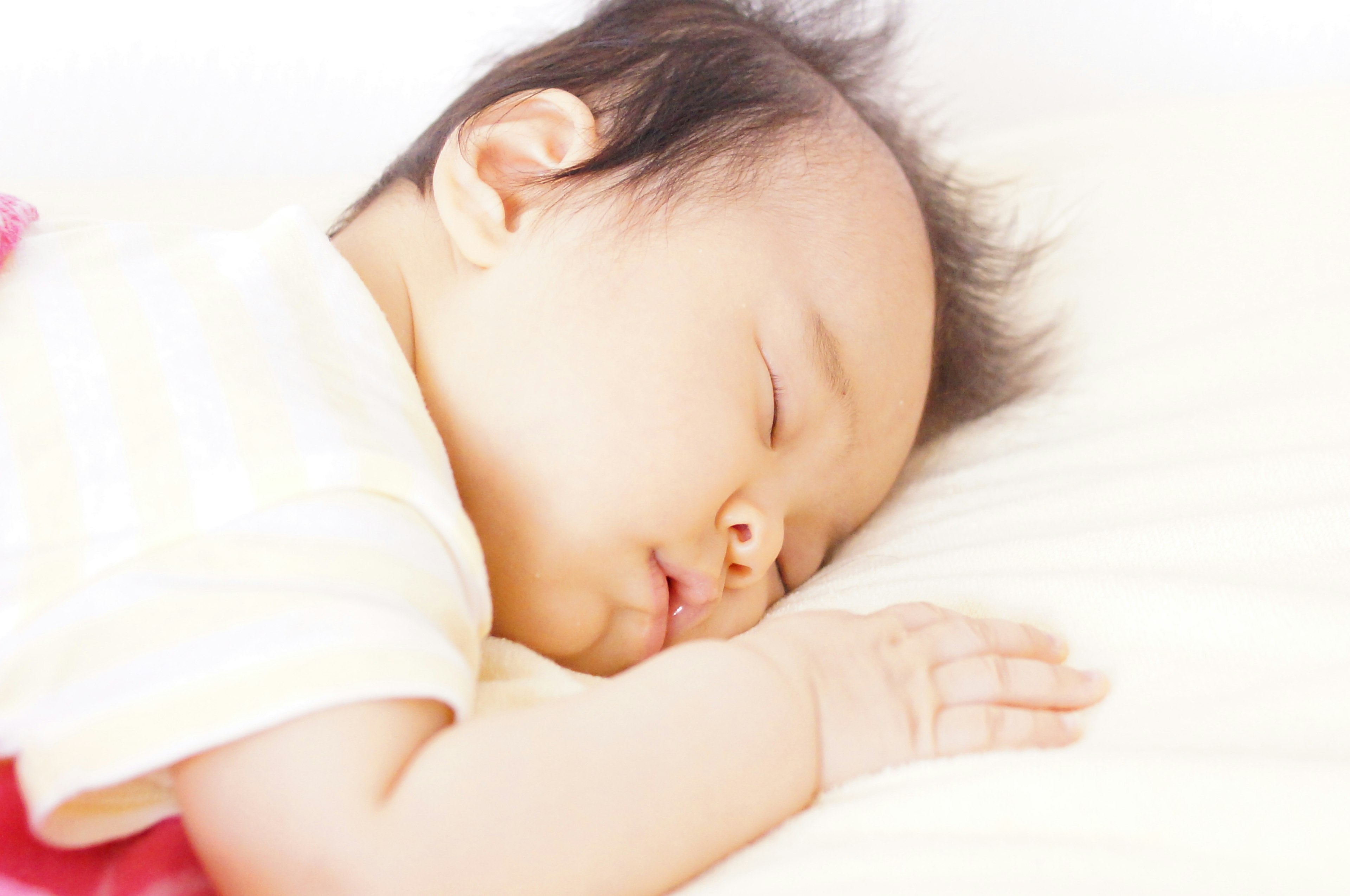 A baby sleeping peacefully on a light-colored pillow