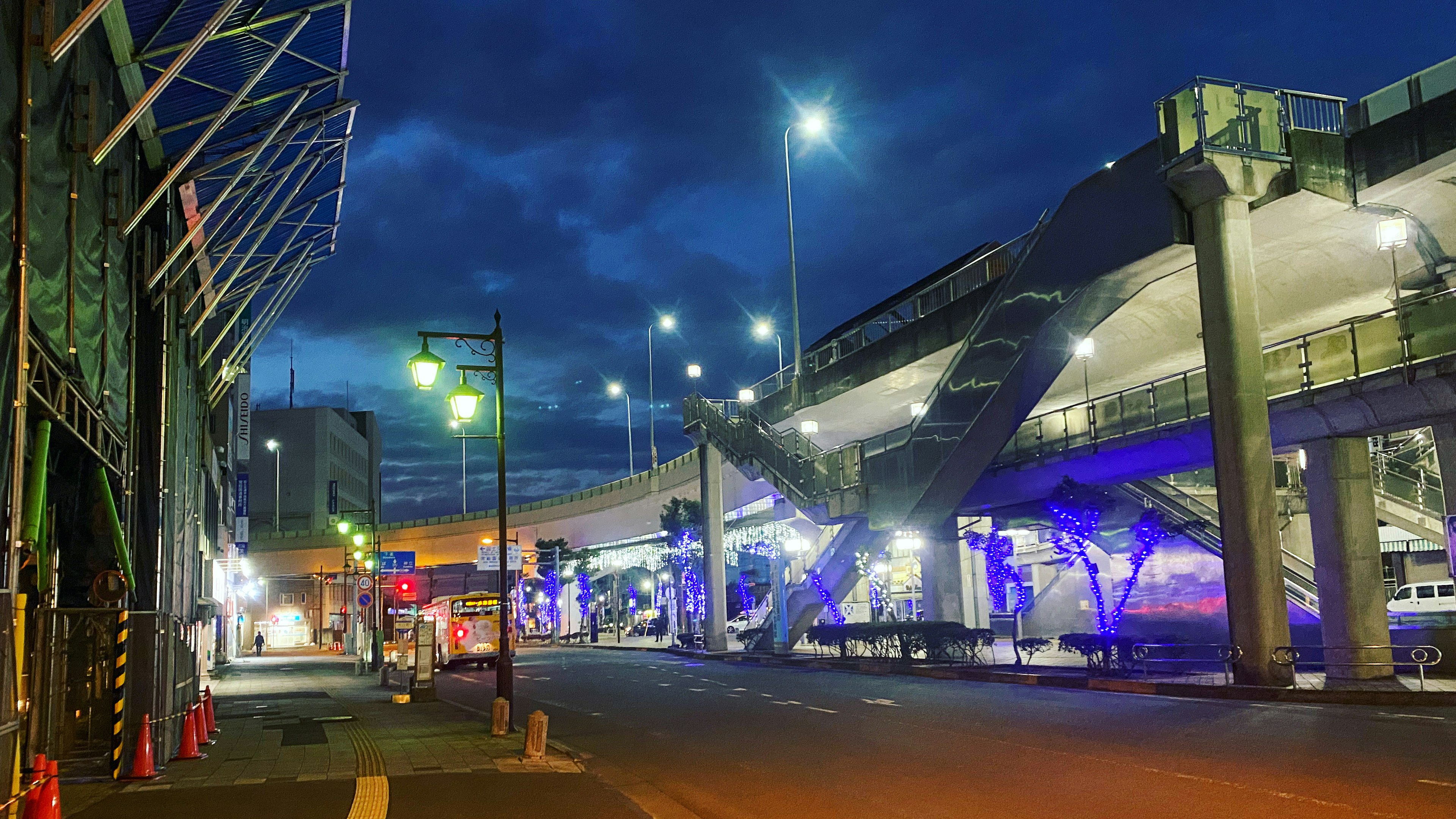 Escena nocturna con un puente elevado de transporte iluminado y una calle