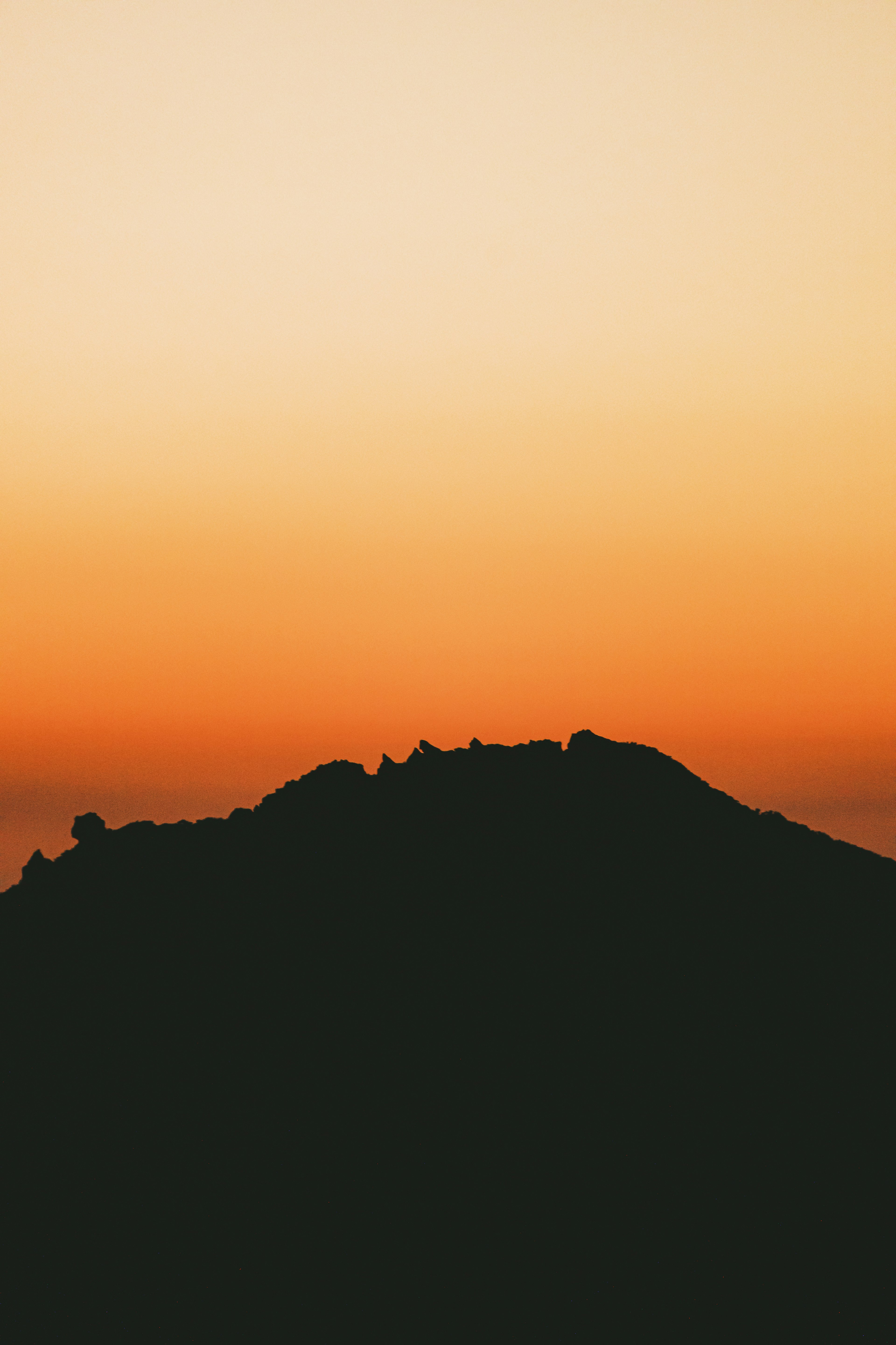 夕焼けのオレンジ色の空とシルエットの山