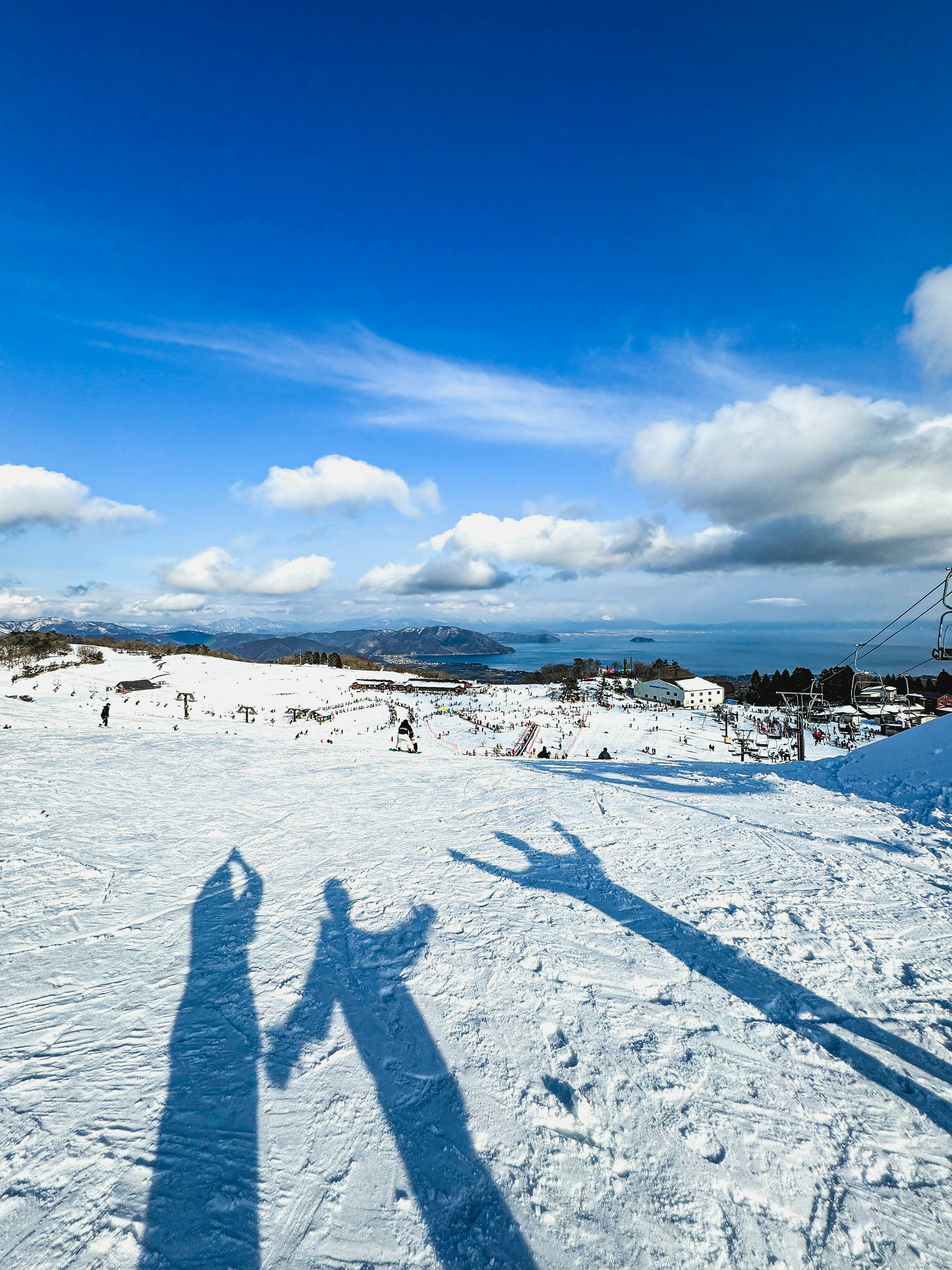 雪の上に映る人々の影と青空の風景