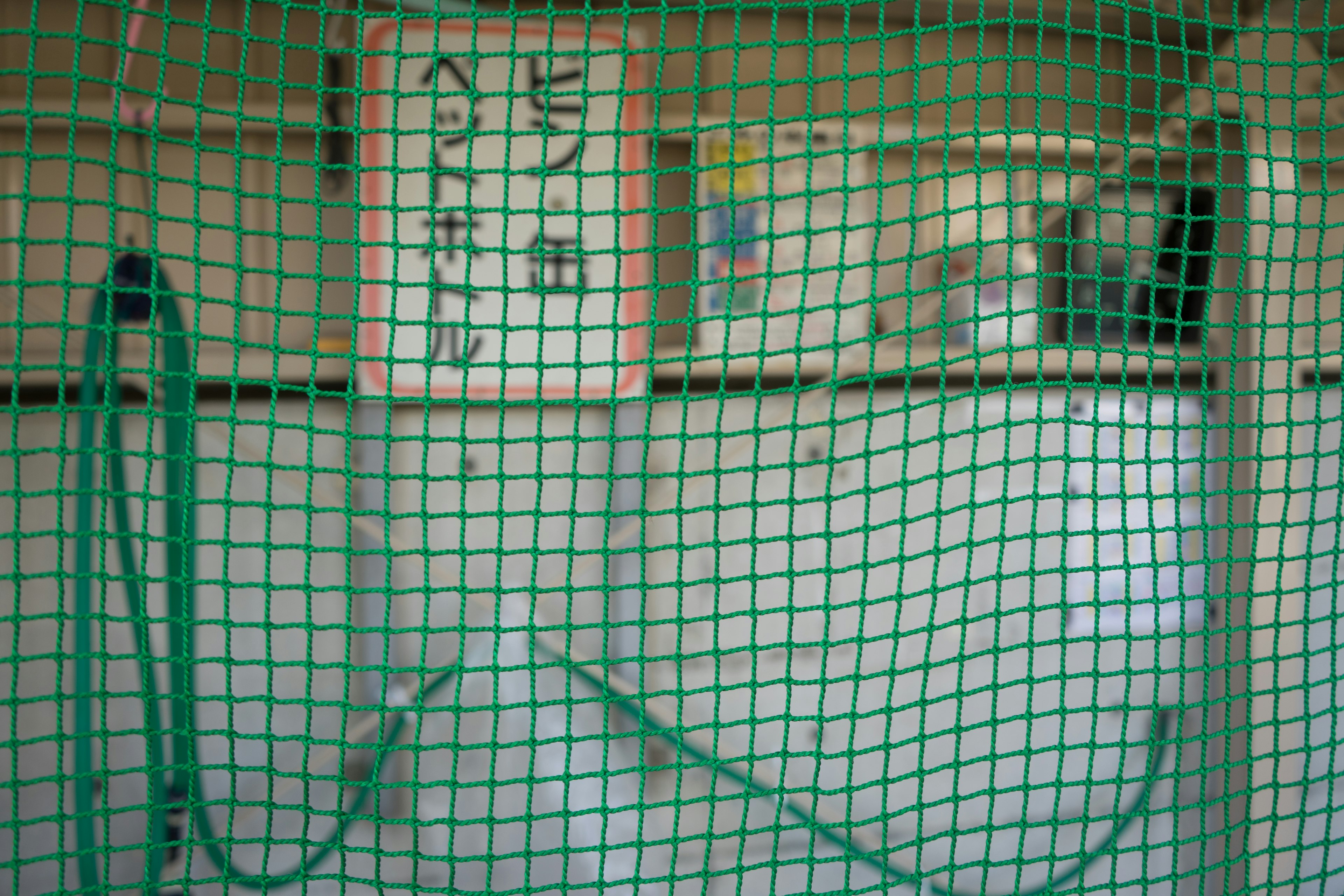 Image of a sign and hose enclosed by green netting