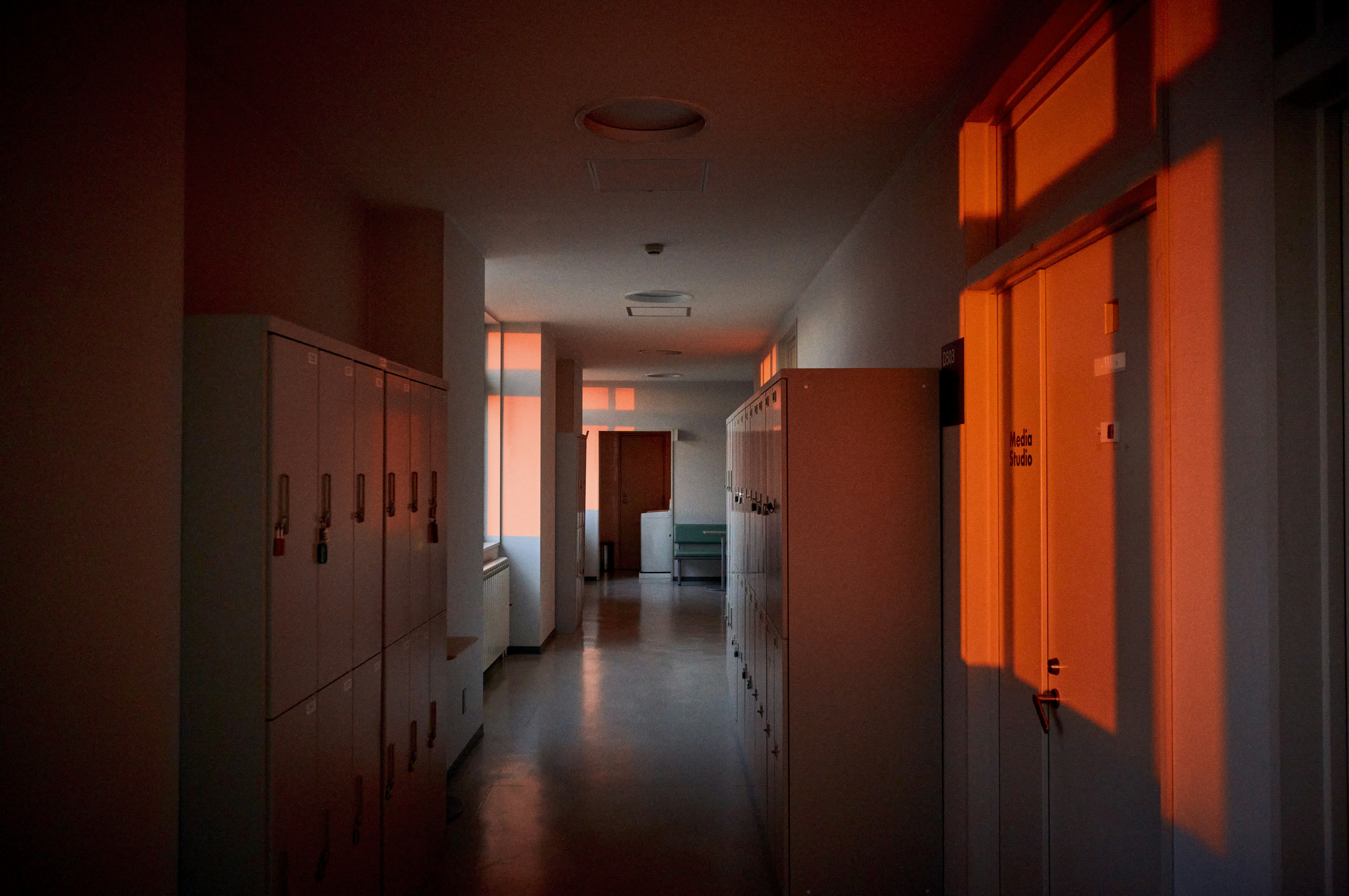 Hallway with orange light streaming in lockers and bright windows