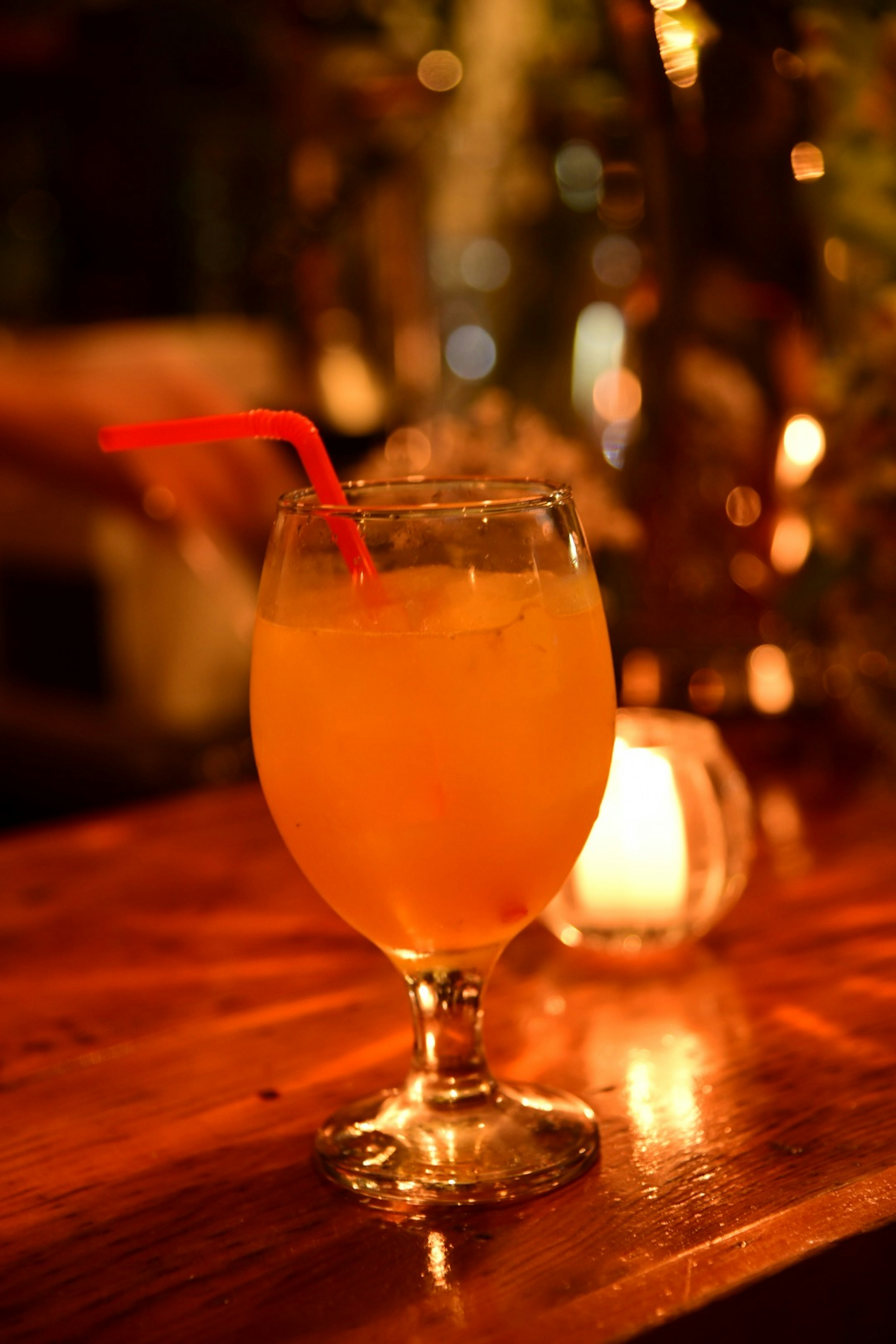 Un verre de cocktail orange avec une paille rouge