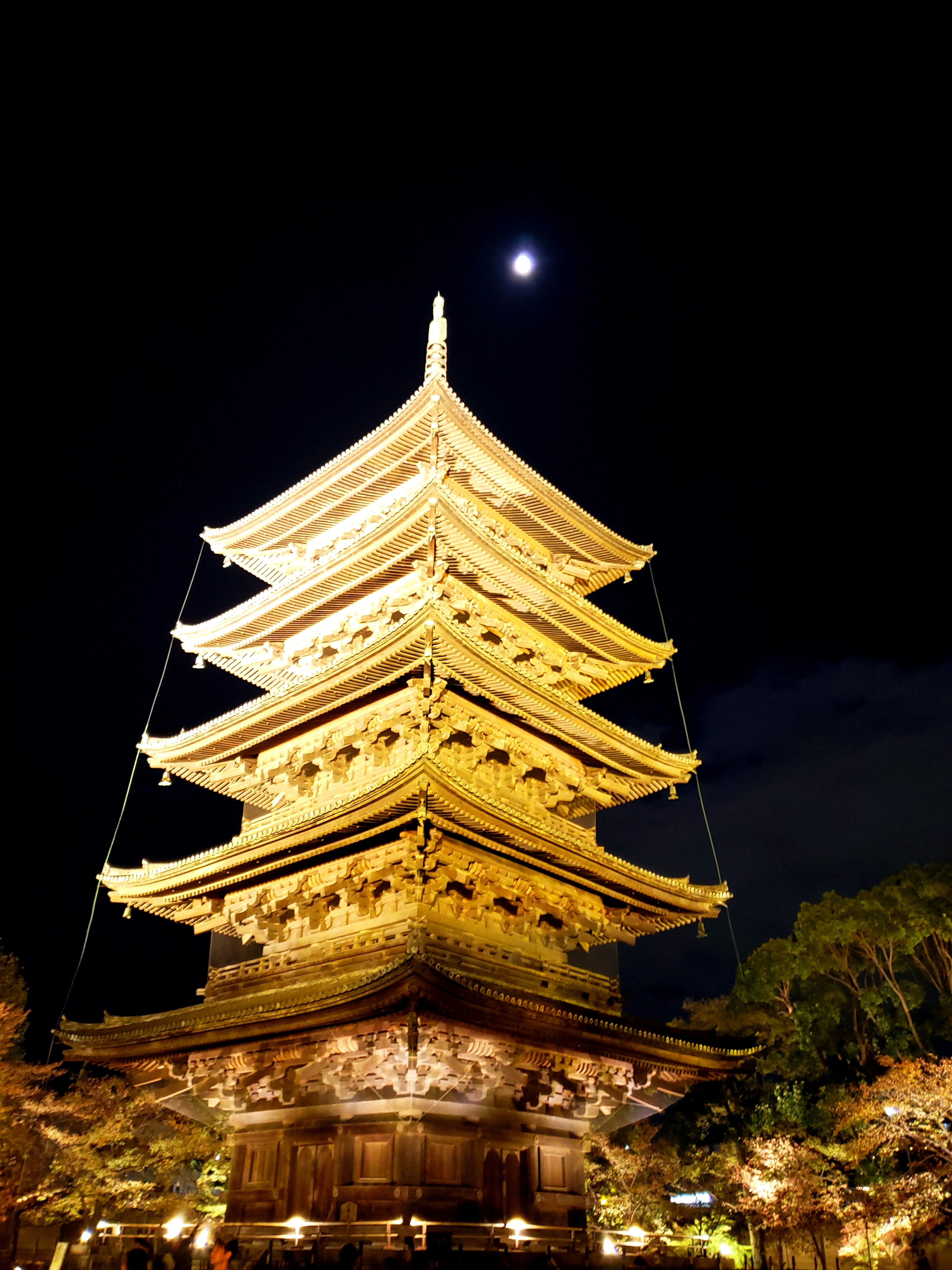 Illuminated pagoda at night with a crescent moon