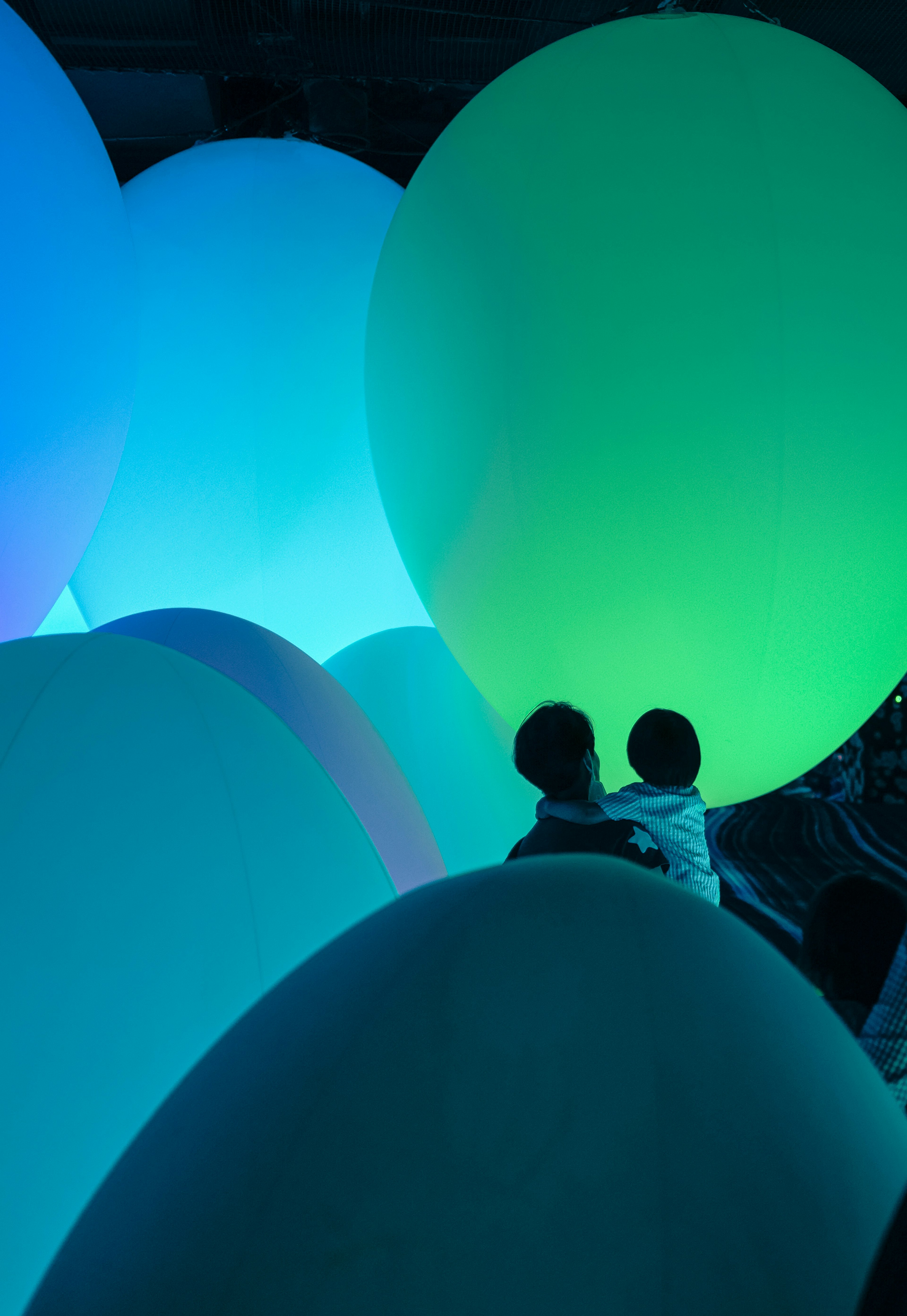 Two people among large glowing blue and green spheres