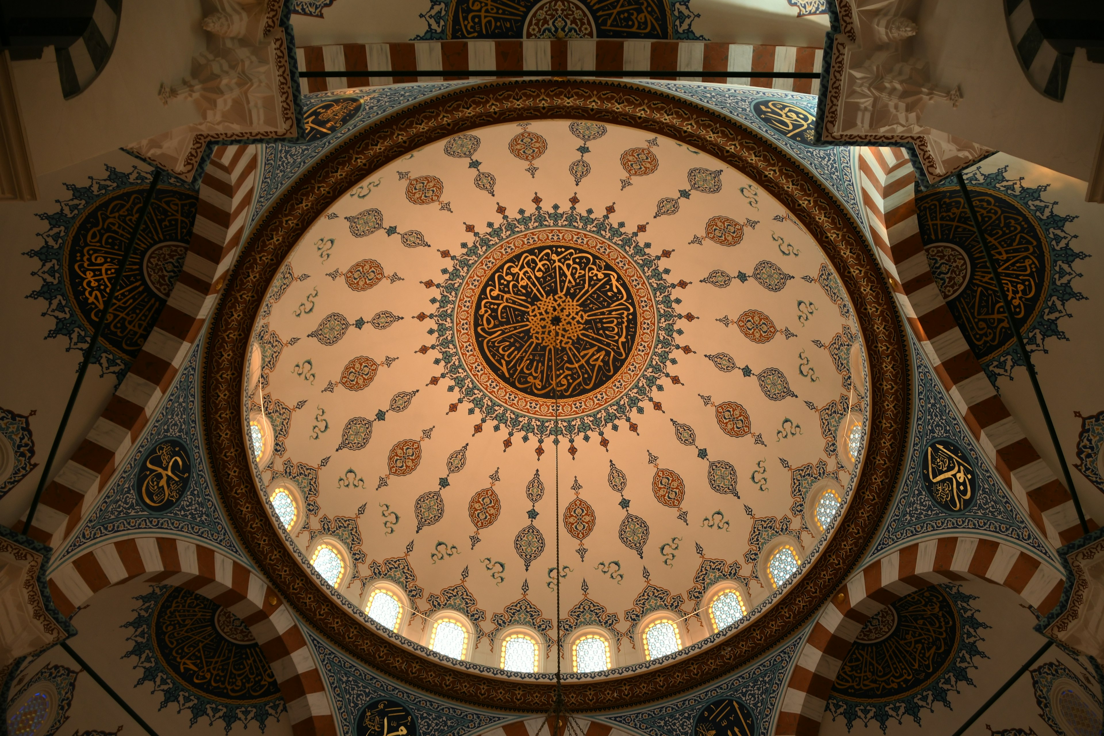 Interior view of a beautifully decorated mosque dome with intricate geometric patterns