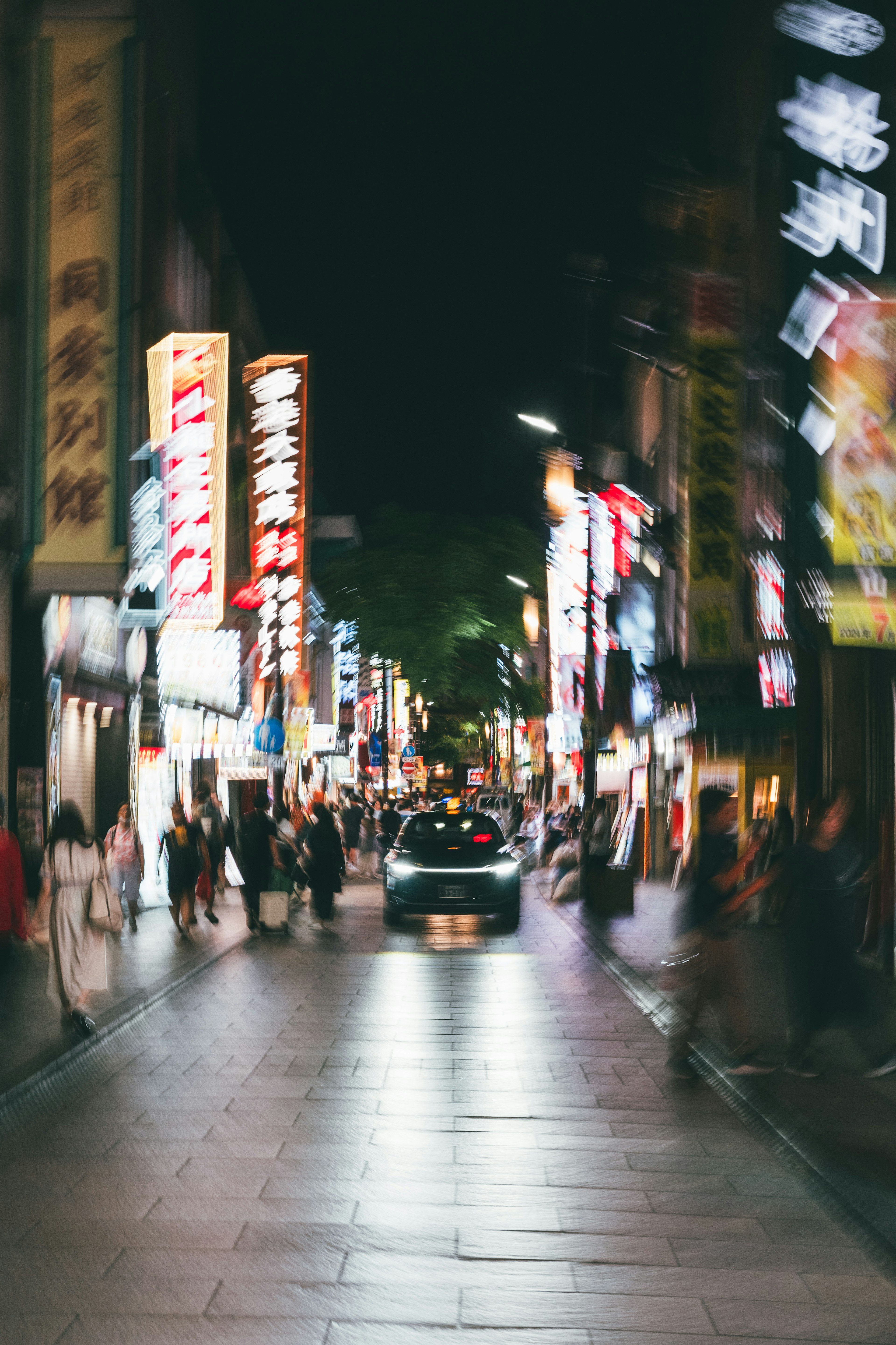 模糊的夜间街景，明亮的招牌和一辆车