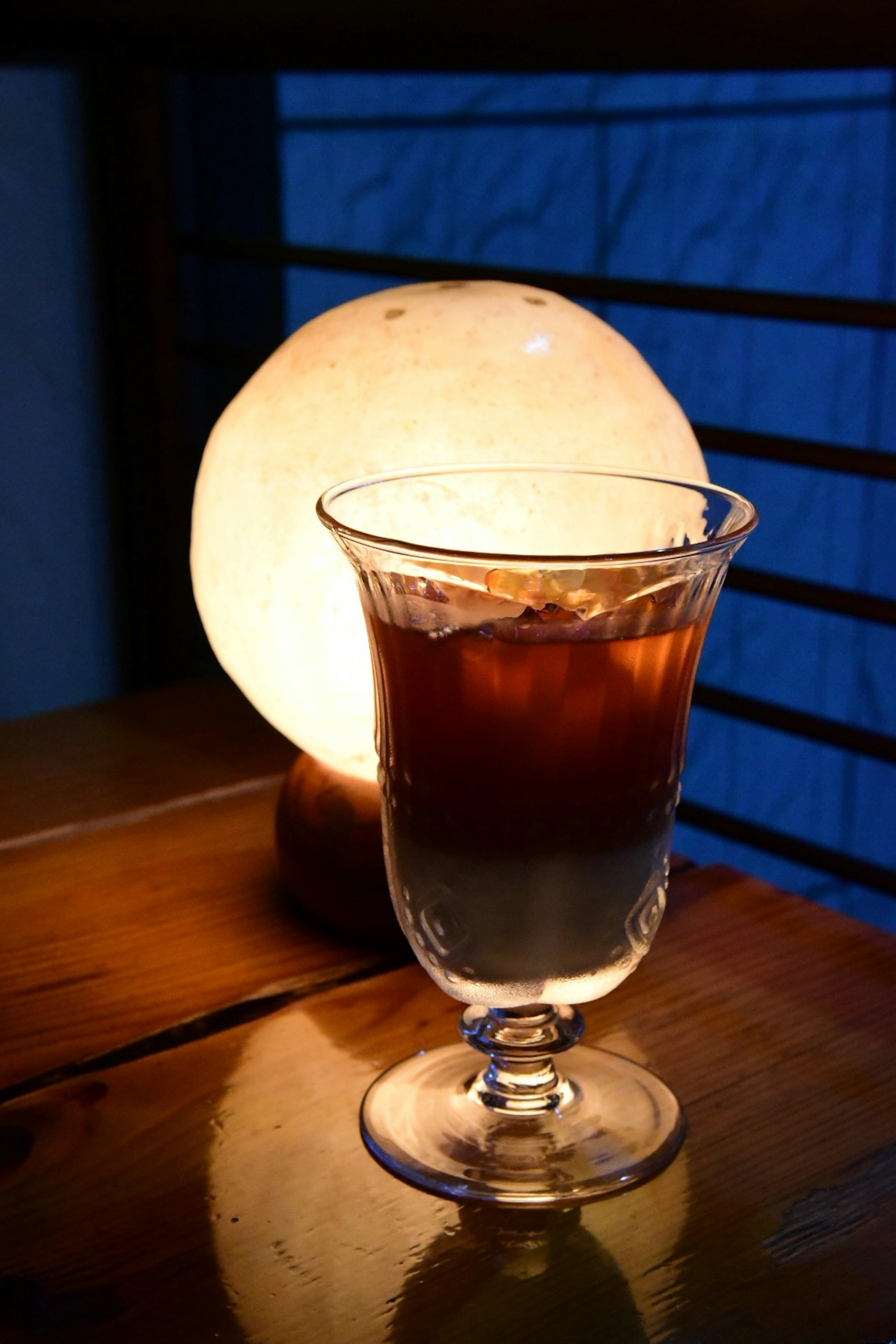 A glass of iced coffee beside a warm glowing lamp