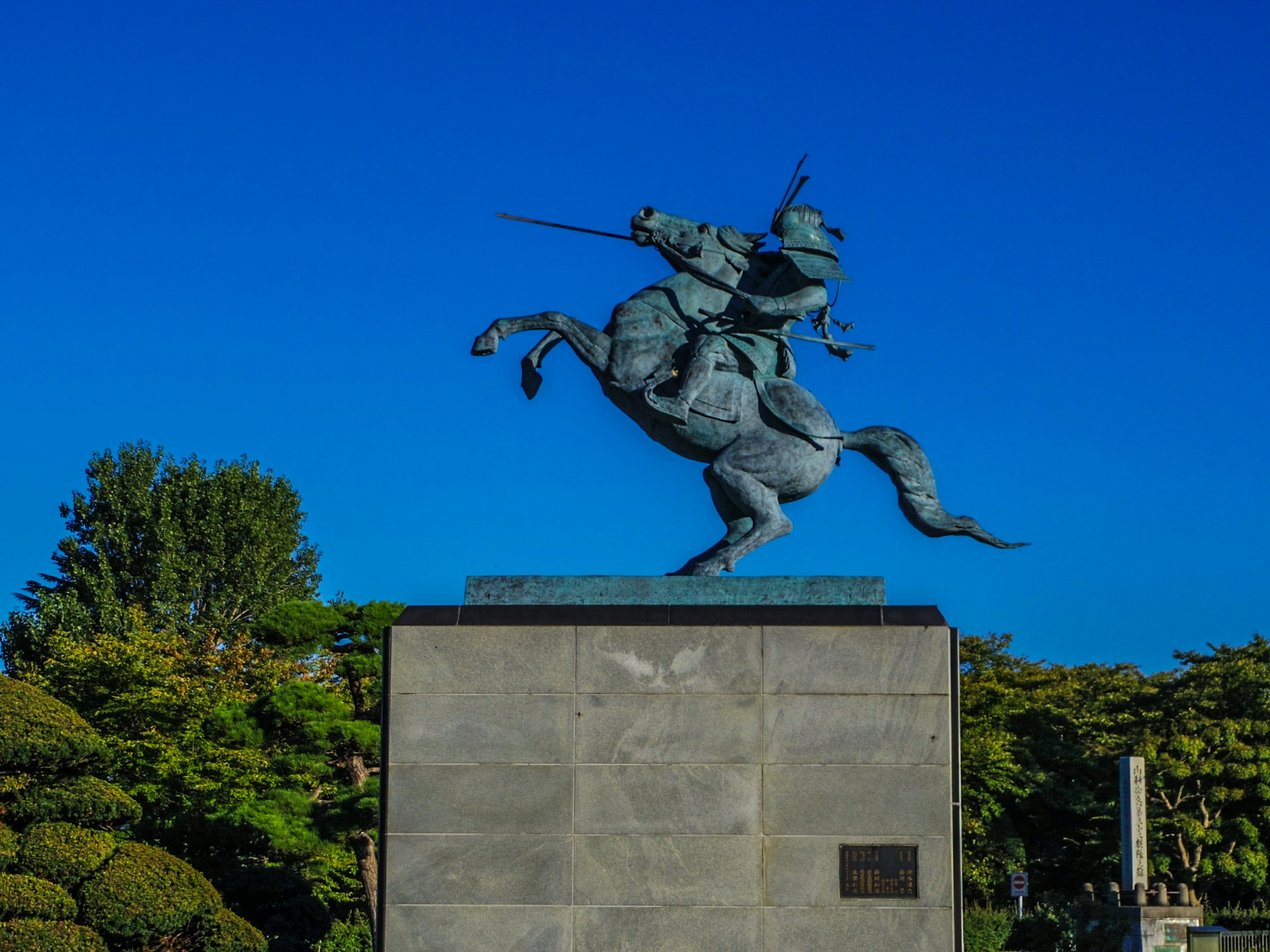 Bronze statue of a knight riding a horse under a clear blue sky