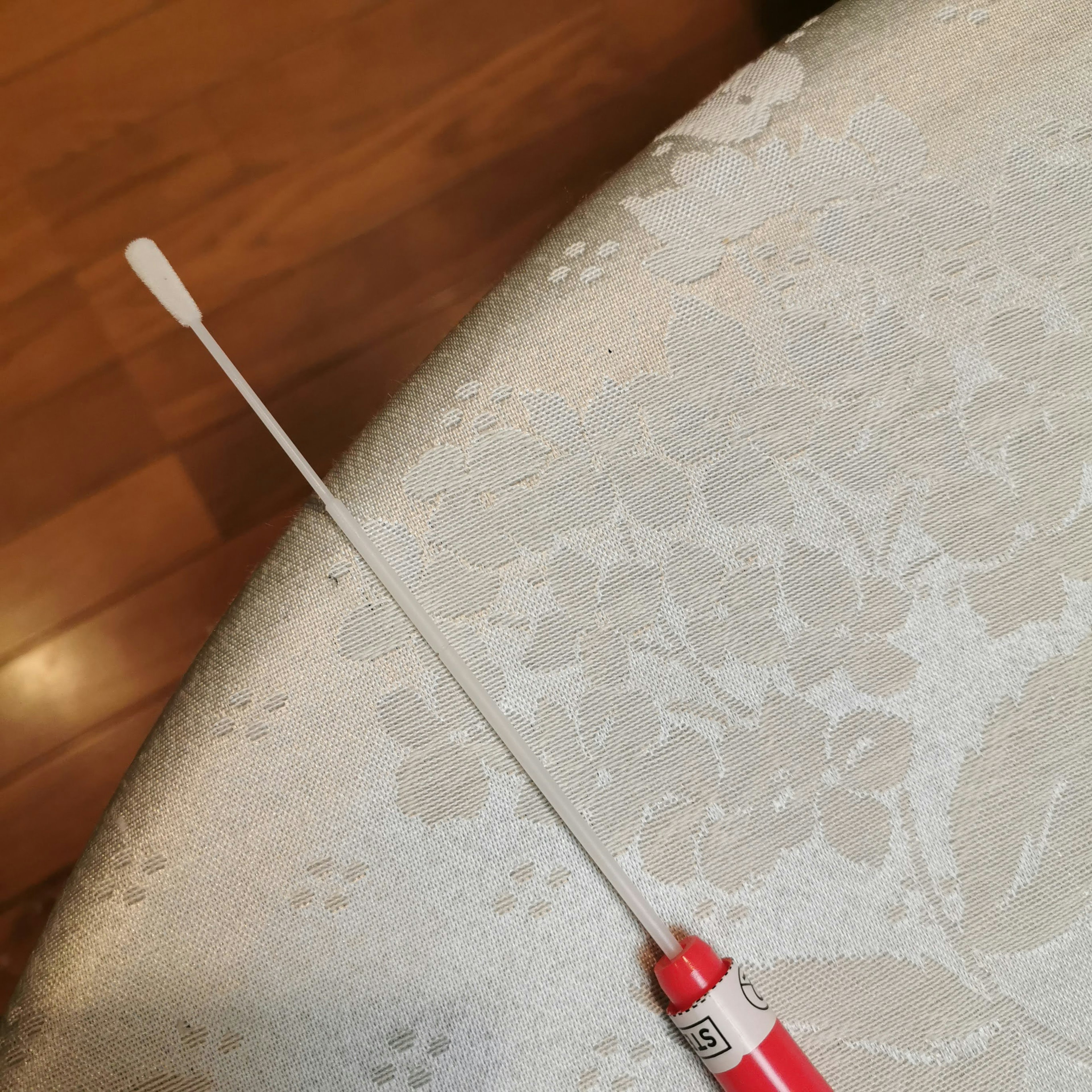 Un outil long en forme de bâton avec un embout rouge posé sur une table