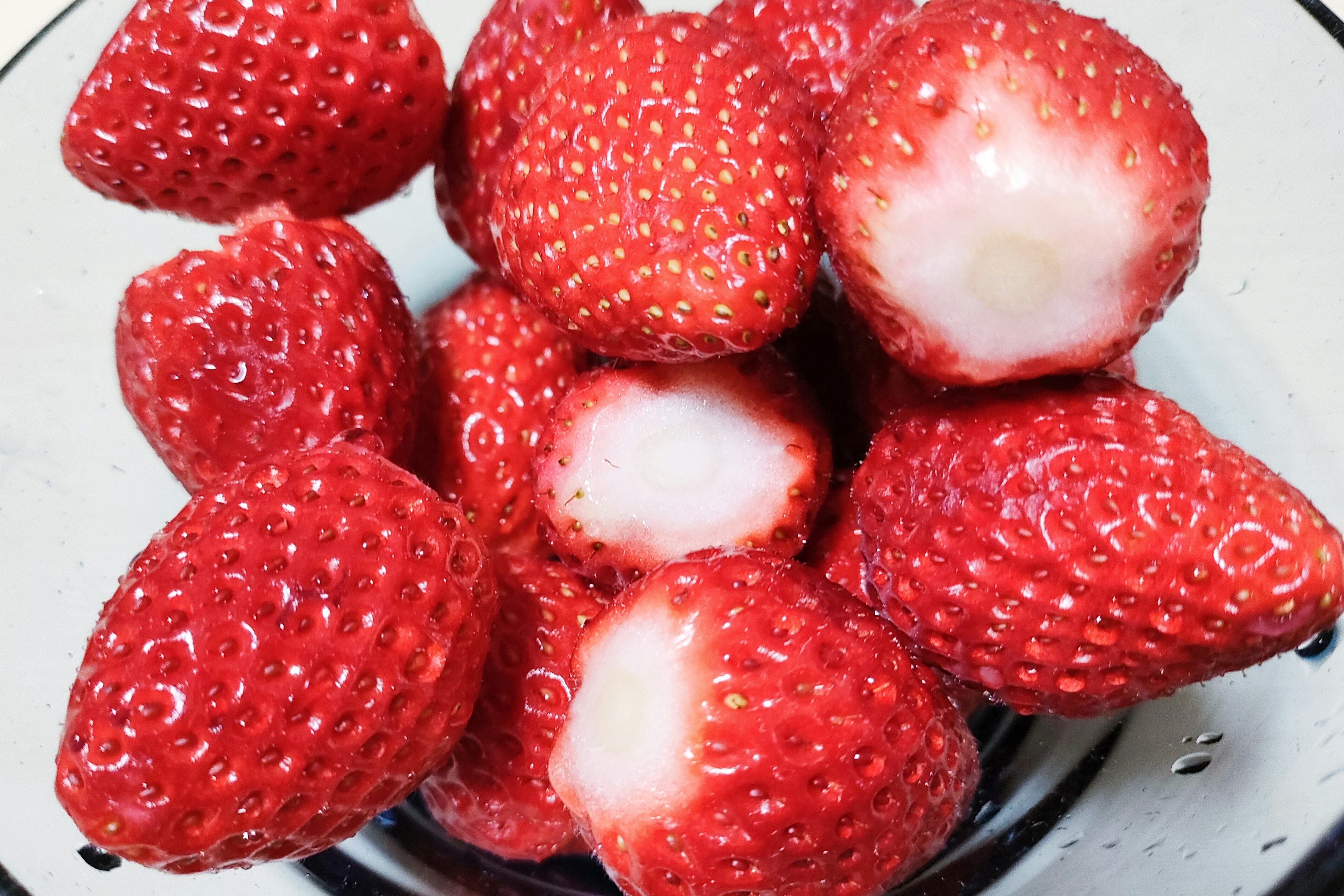 A cluster of fresh strawberries in a clear bowl