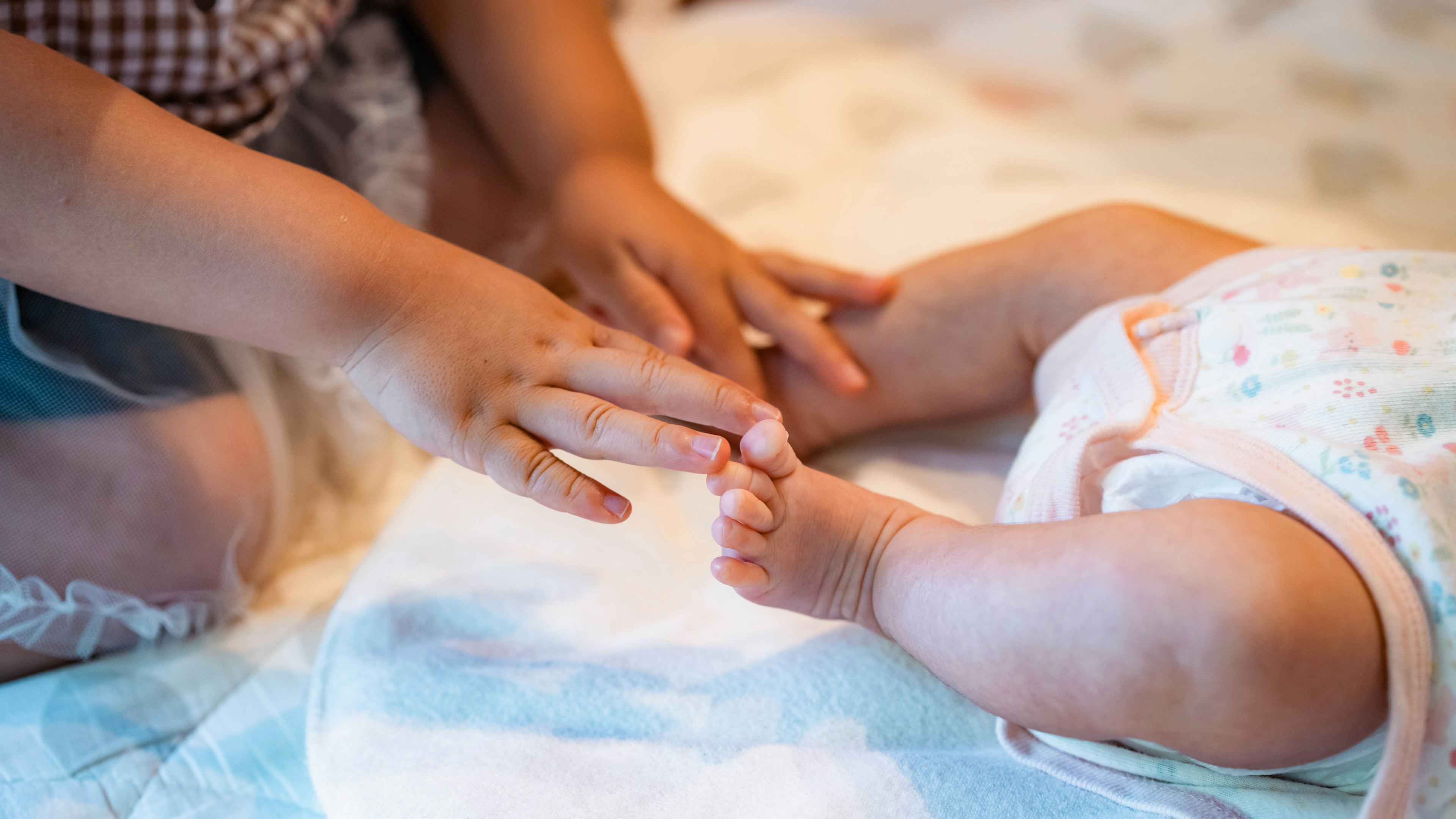 Child's hand reaching for a baby's foot